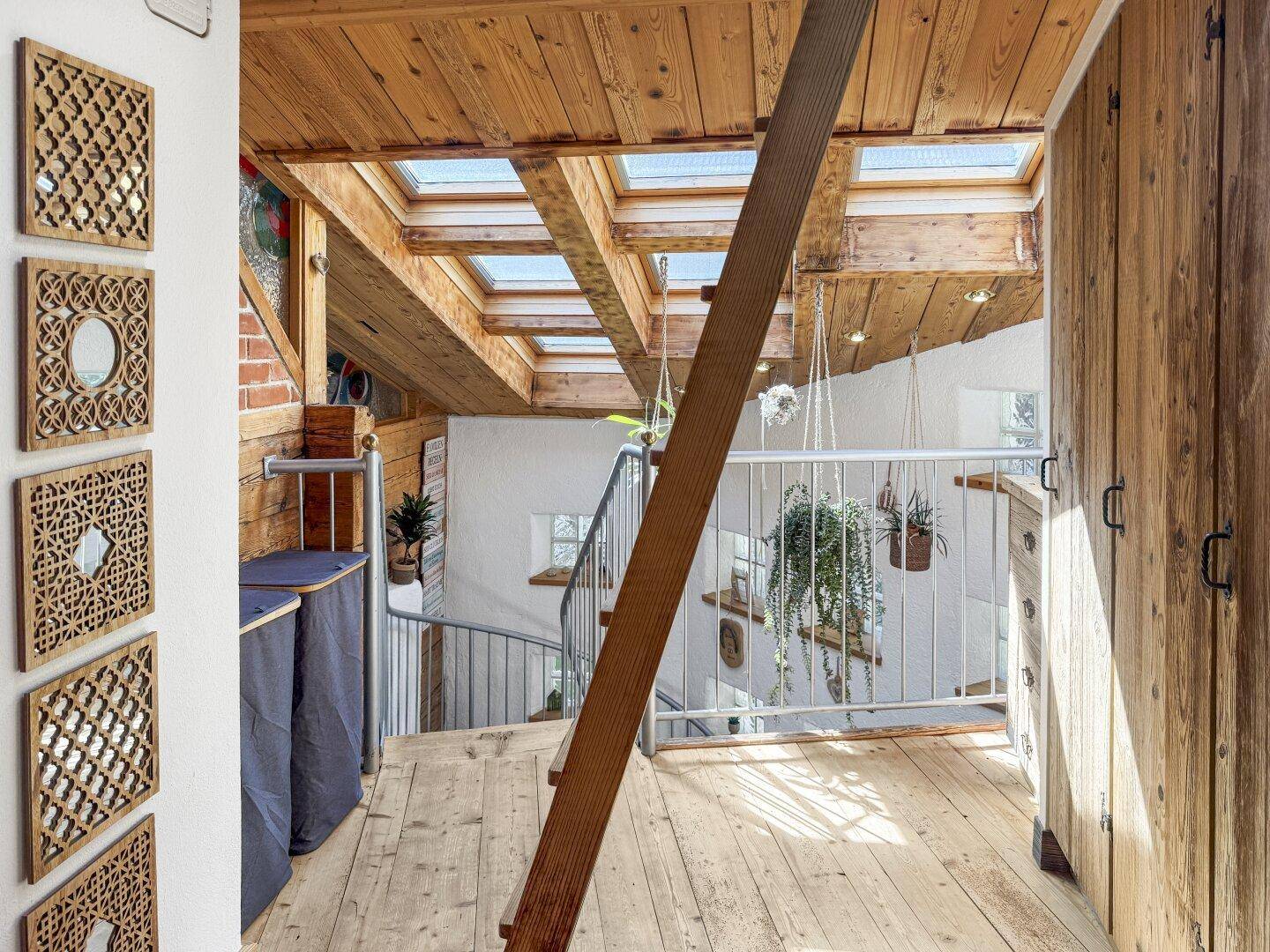Obergeschoss-Flur mit Holzbalkendecke, Dachfenstern und integrierten Holzschränken.