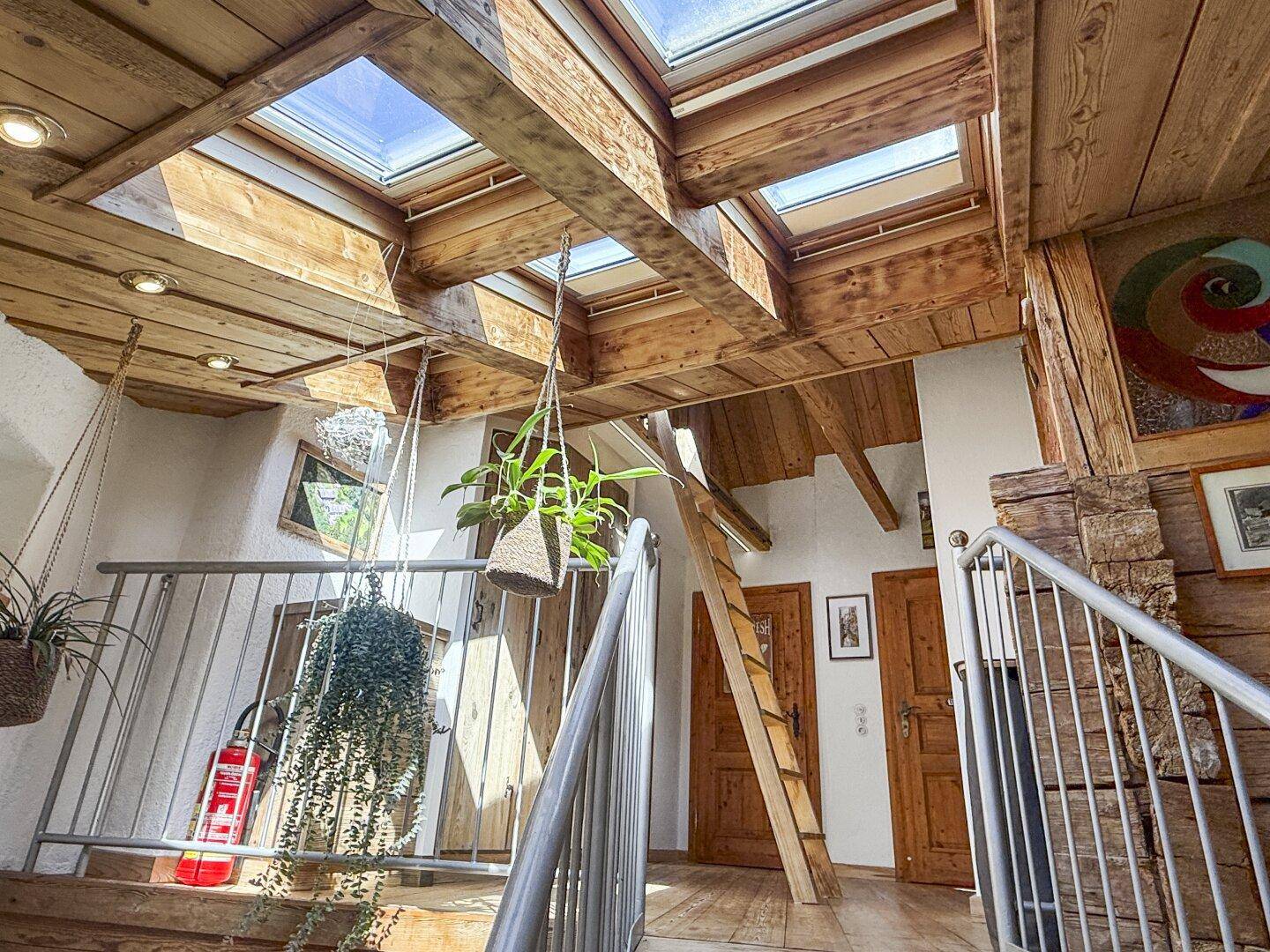 Heller Flur im Obergeschoss mit Holzbalkendecke, Dachfenstern und Zugang zu weiteren Räumen.