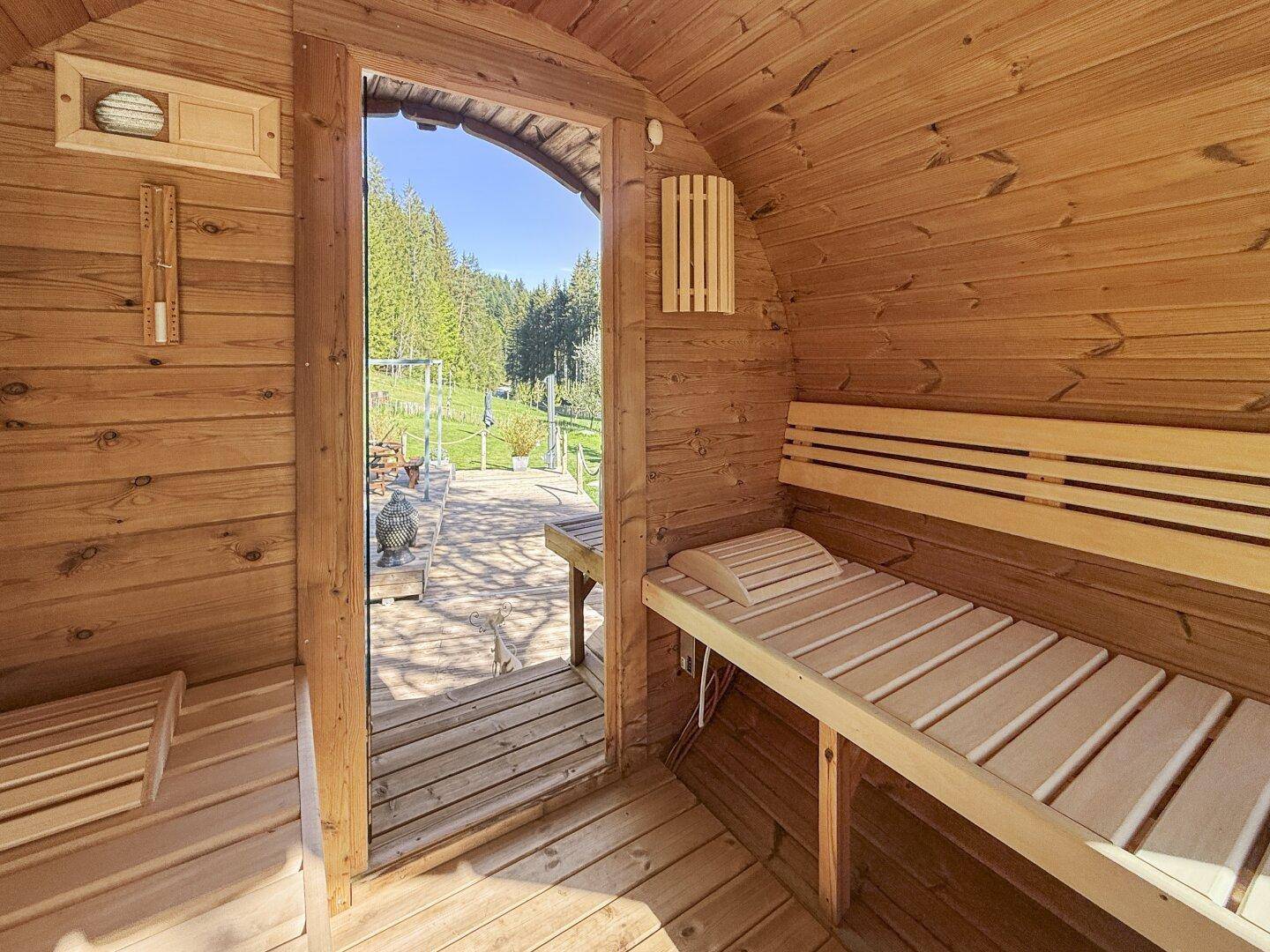 Gemütliche Holzsauna mit Blick ins Grüne und bequemen Bänken für Entspannung.