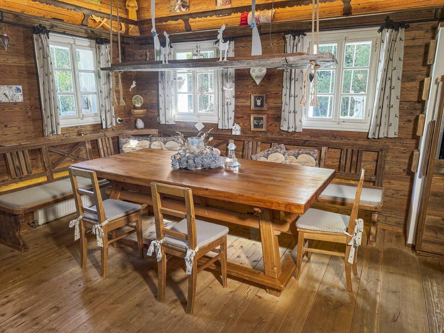 Geräumiger Essbereich mit großem Holztisch, Eckbank und Holzbalkendecke im alpinen Stil.