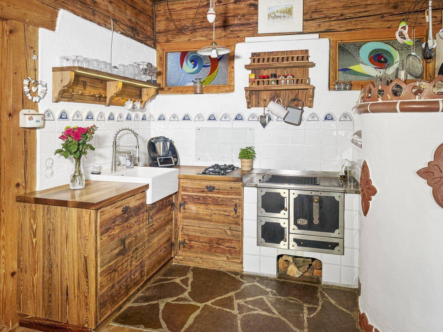Traditionelle Küche mit Holzherd, Spülbecken und rustikalen Holzschränken, ideal für Landleben.