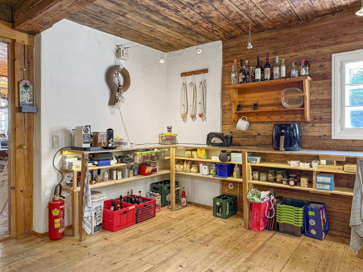 Gut organisierte Speisekammer mit Holzregalen, gefüllt mit Vorräten und Getränken.