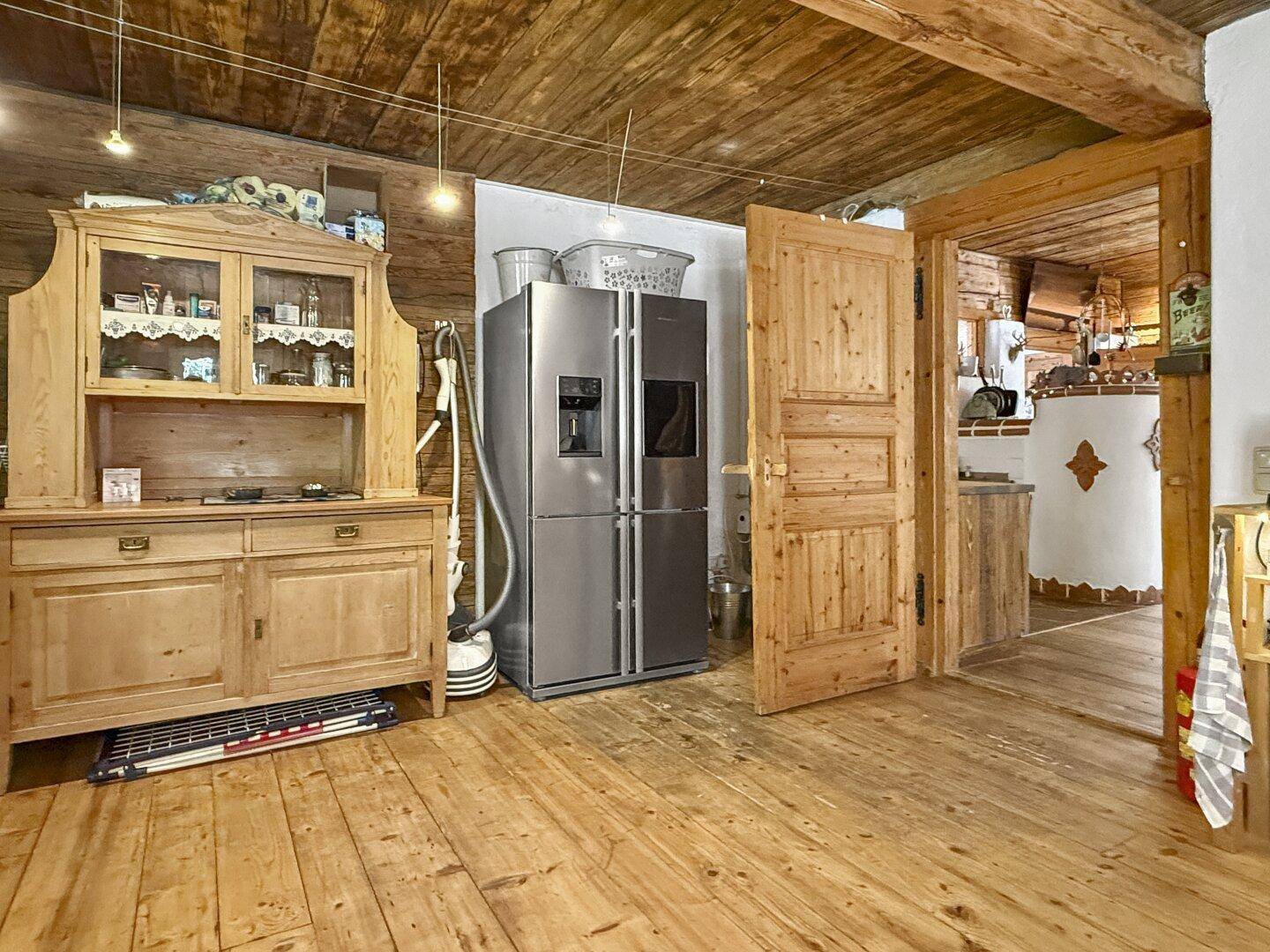 Praktischer Abstellraum mit großem Kühlschrank, Holzschrank und Zugang zu weiteren Räumen.