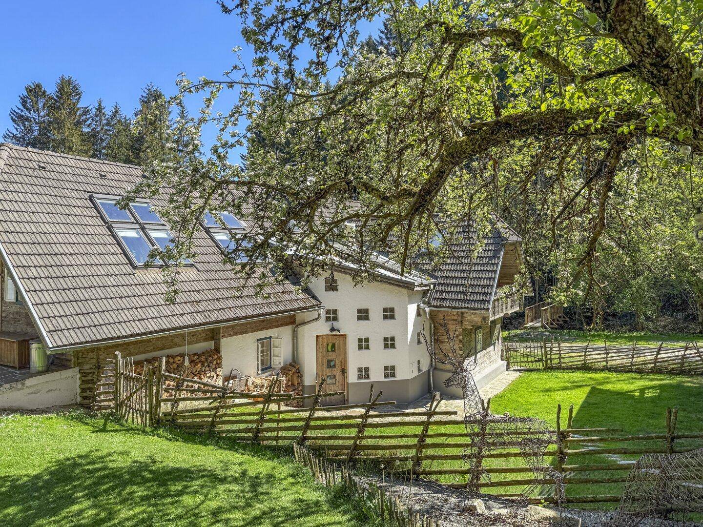 Traditionelles Haus mit weißer Fassade, Holzdetails und einem gepflegten Gartenbereich.