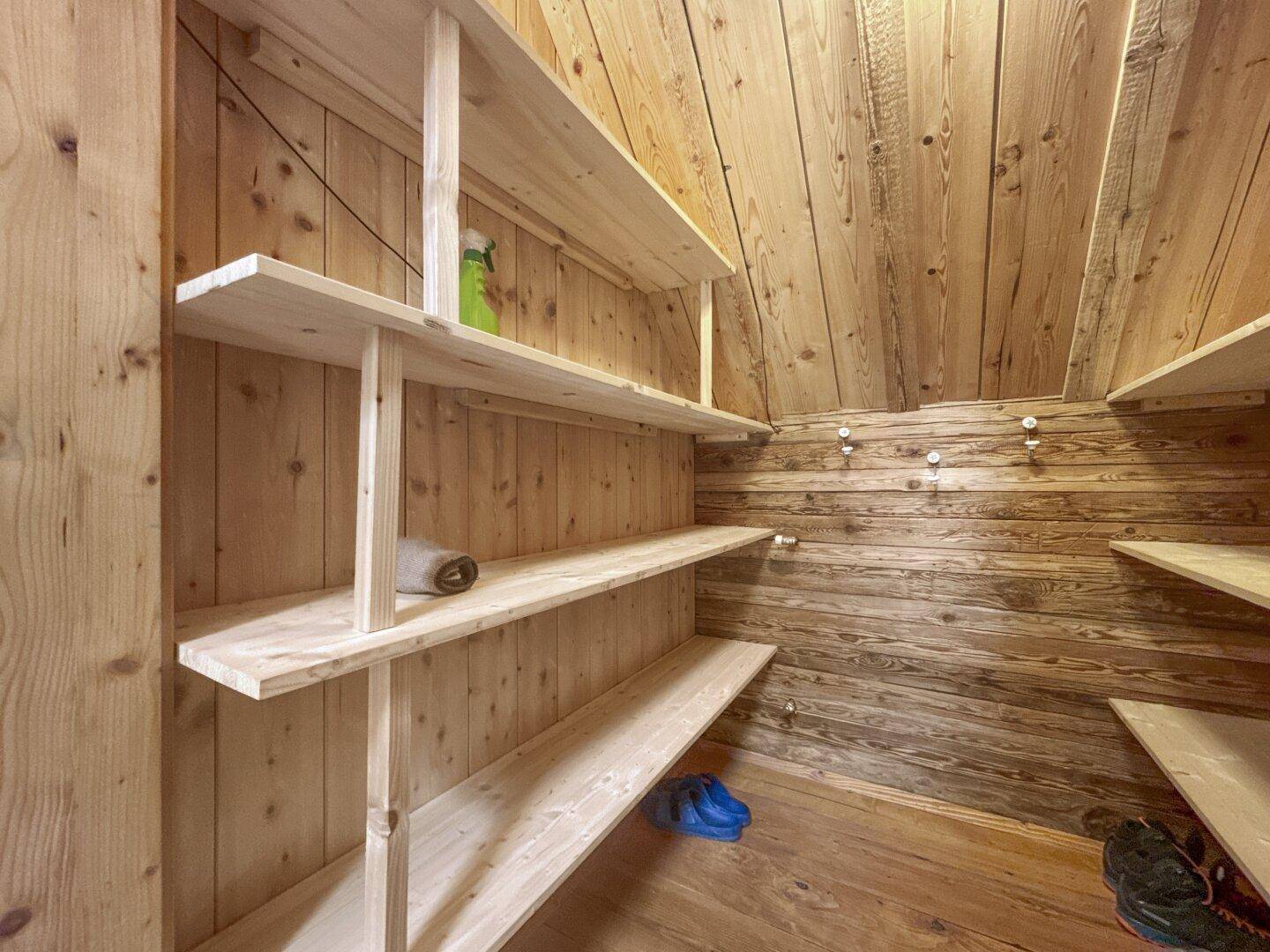 Praktischer Abstellraum mit Holzverkleidung, schrägen Wänden und offenen Regalen für Stauraum.