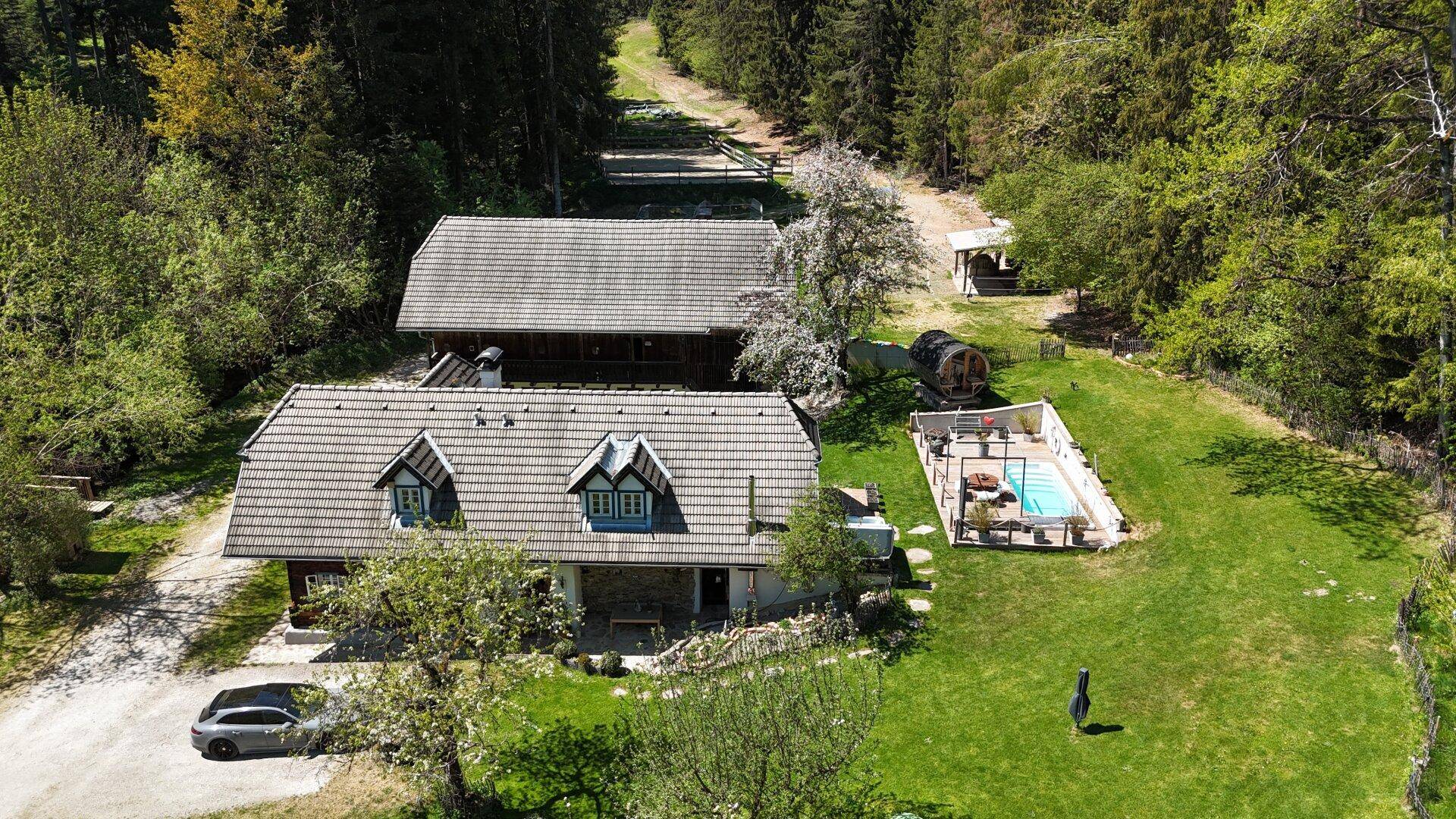 Luftaufnahme des Anwesens mit Haupthaus, Pool, Whirlpool und Fasssauna, inklusive geparktem Auto.