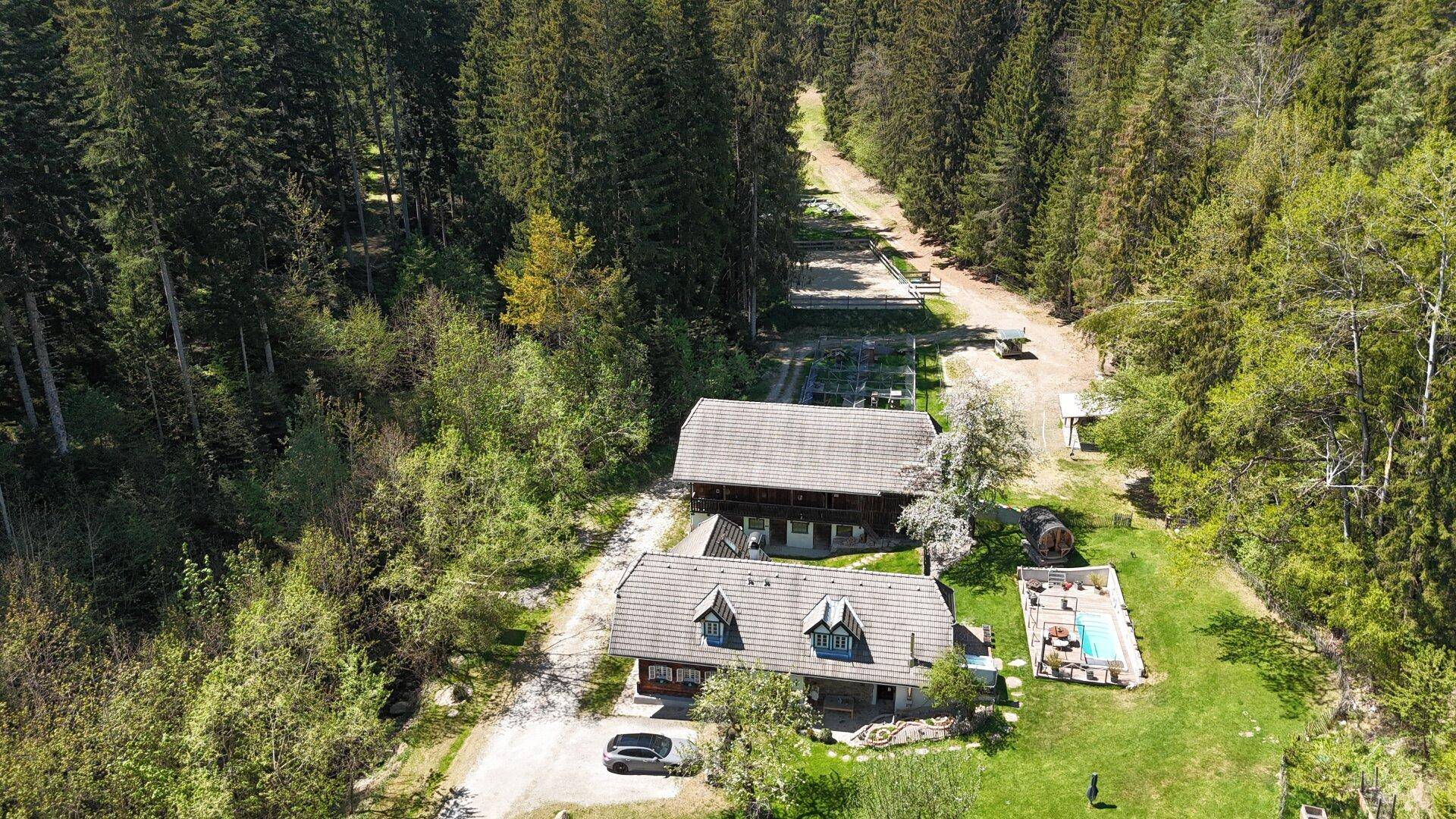 Weitläufige Luftaufnahme des Anwesens mit Haupthaus, Pool, Whirlpool und Sauna, umgeben von Wald.