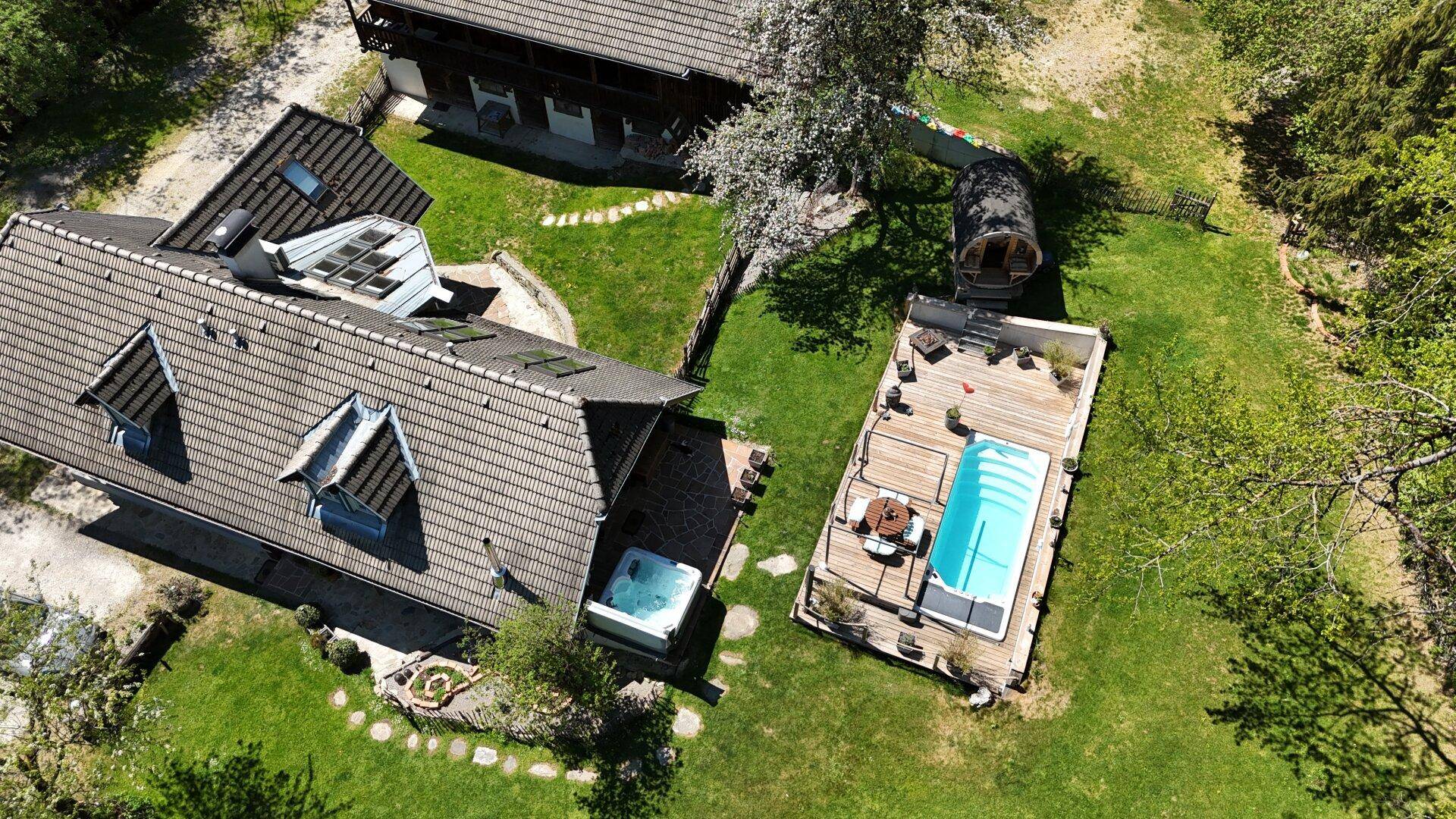Luftaufnahme des Anwesens mit Haupthaus, Pool, Whirlpool und Fasssauna inmitten grüner Natur.