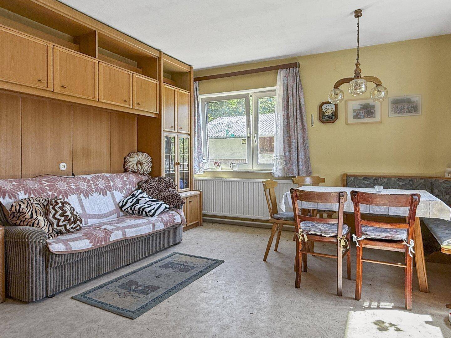Wohn- und Essbereich mit Sofa, Esstisch und einer Holzschrankwand, in traditionellem Stil.