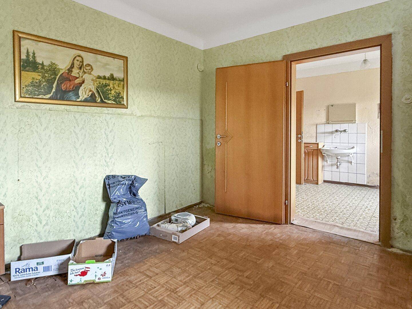 Raum mit einfacher Ausstattung und Zugang zu einem Badezimmer mit Waschbecken.
