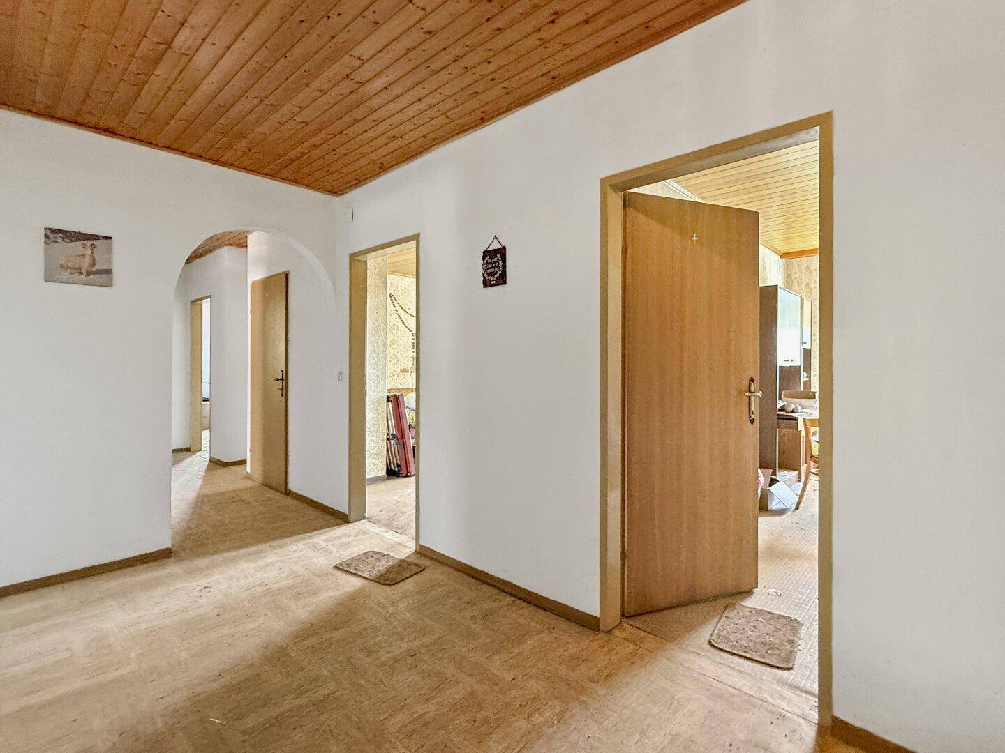 Heller Flur mit Holzdecke und mehreren Türen, die zu verschiedenen Räumen führen.