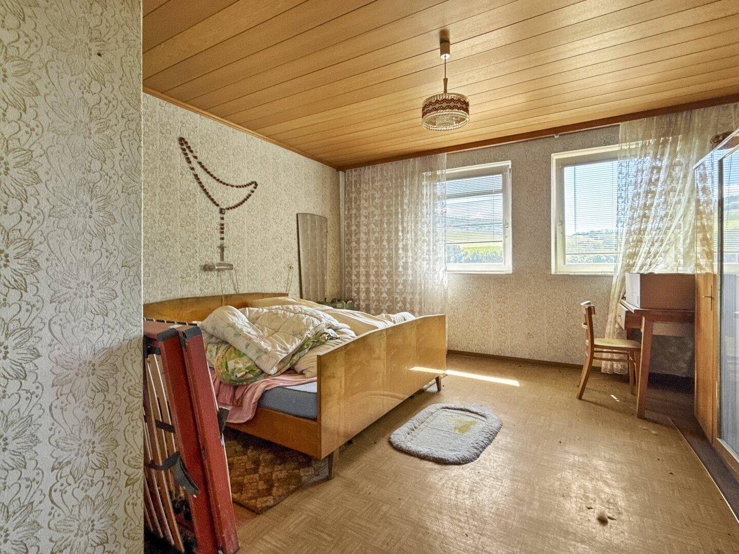 Schlafzimmer mit zwei Fenstern, die einen weiten Blick in die Landschaft bieten.