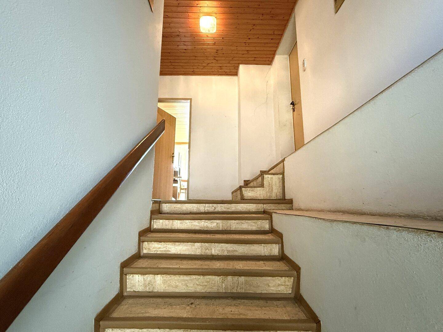 Treppenhaus mit Holzdecke und Holzgeländer, das in die obere Etage führt.