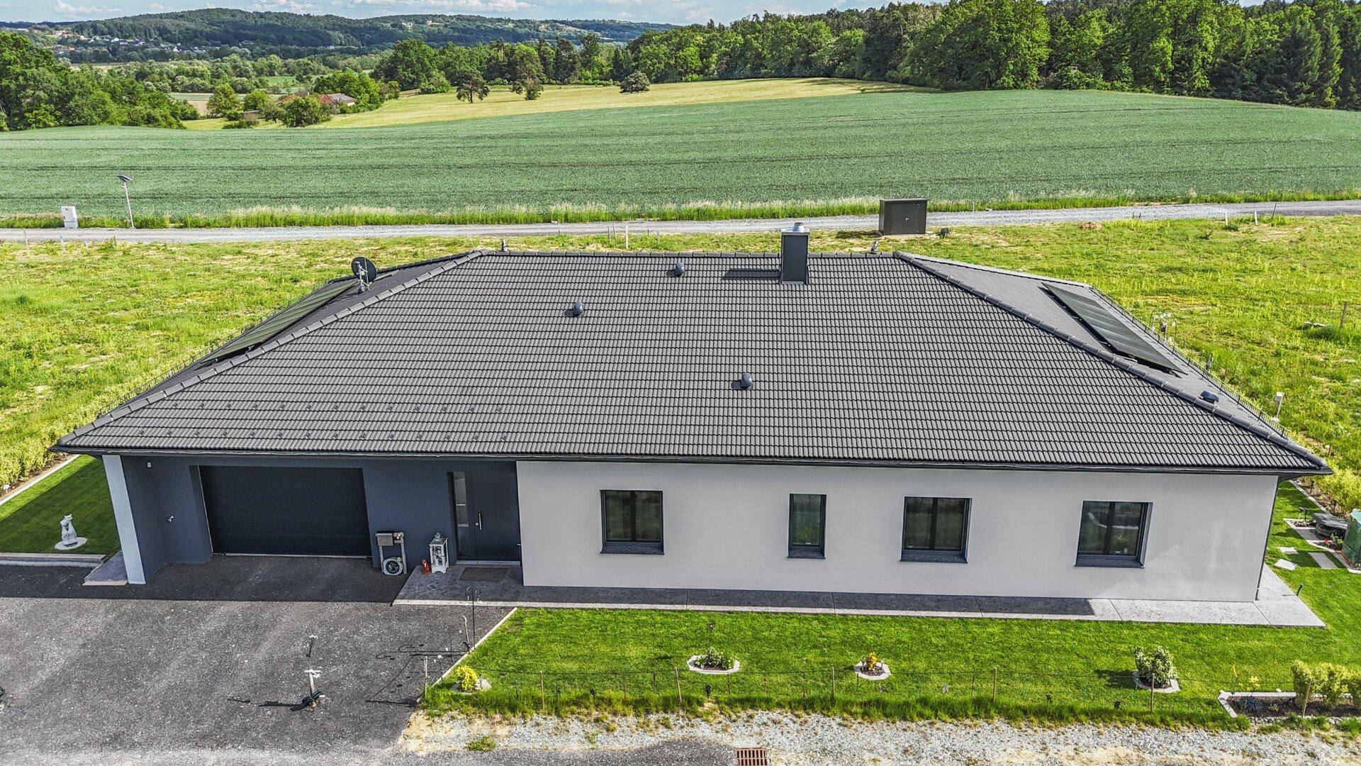 Vogelperspektive auf ein neues Einfamilienhaus mit integrierter Garage und Photovoltaikmodulen auf dem Dach.
