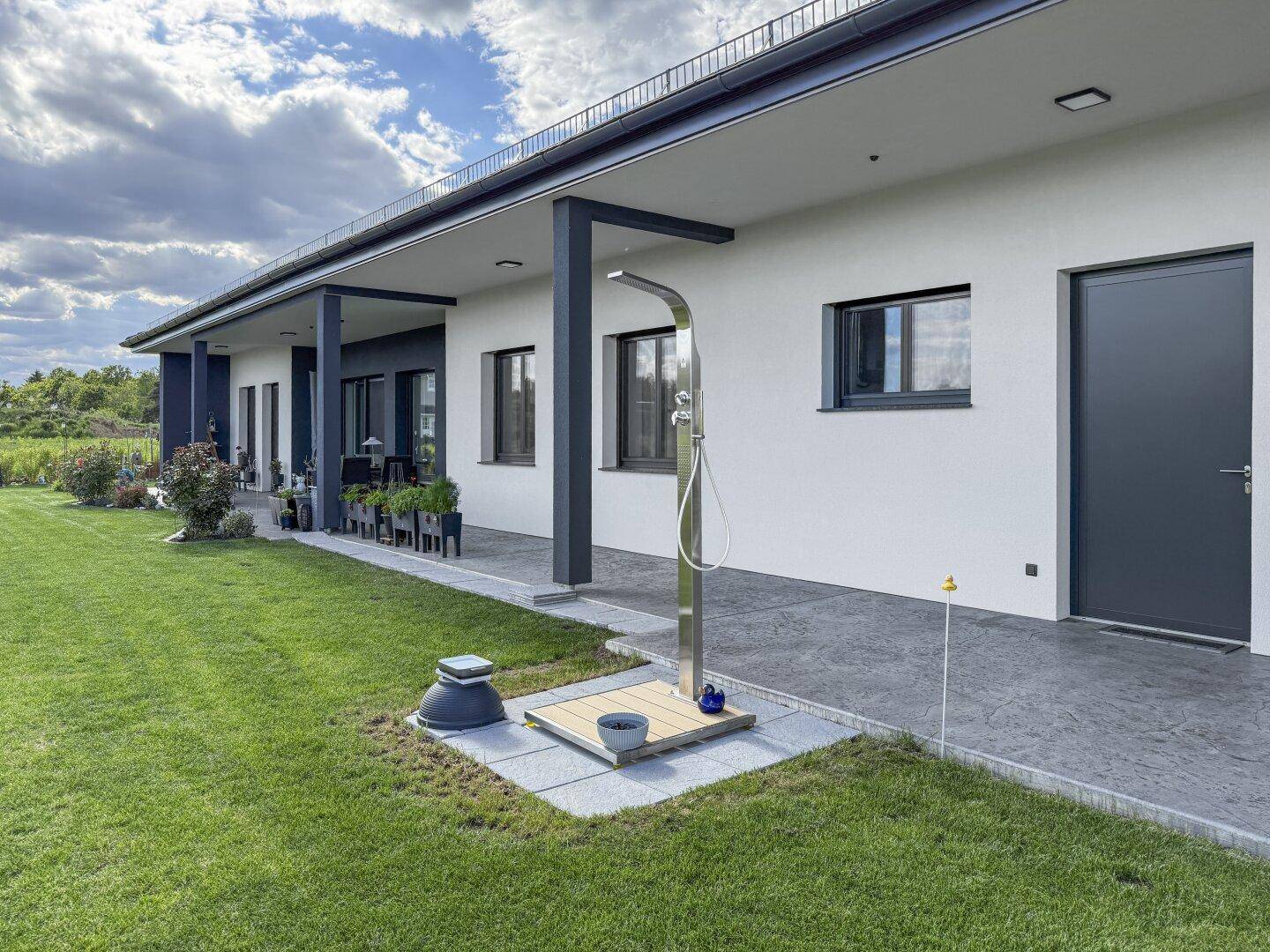 Gepflegter Gartenbereich mit einer modernen Außendusche und direktem Zugang zum Haus.