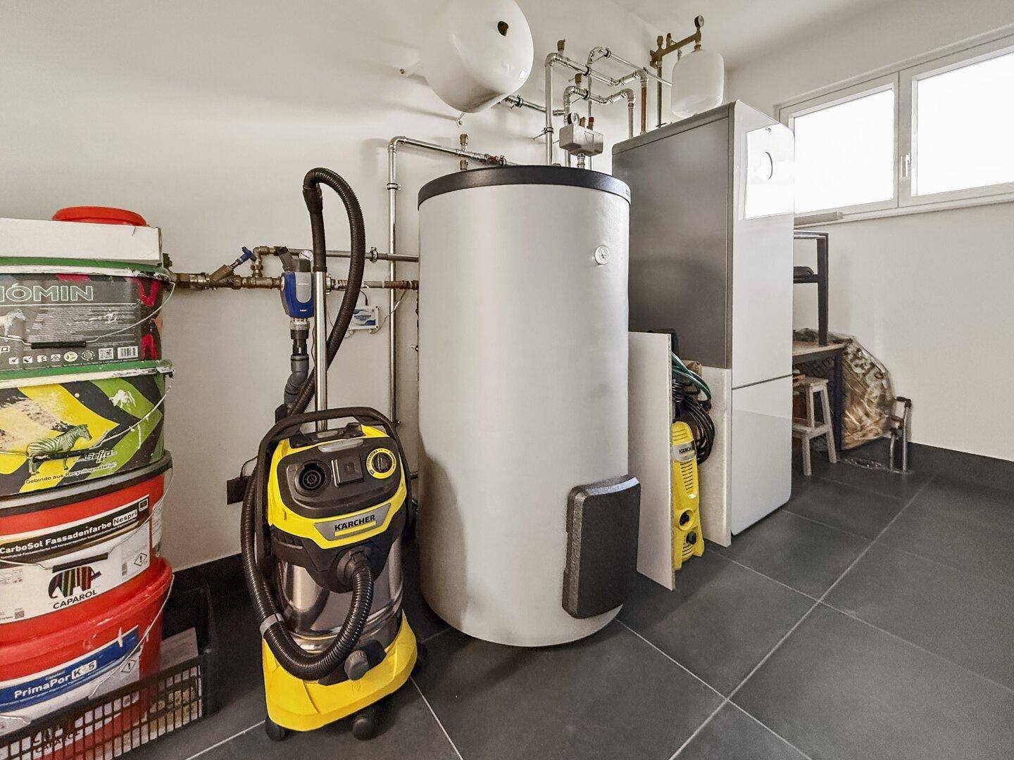 Technikraum mit Warmwasserspeicher, Heizungsanlage und praktischem Fliesenboden für Wartungsarbeiten.