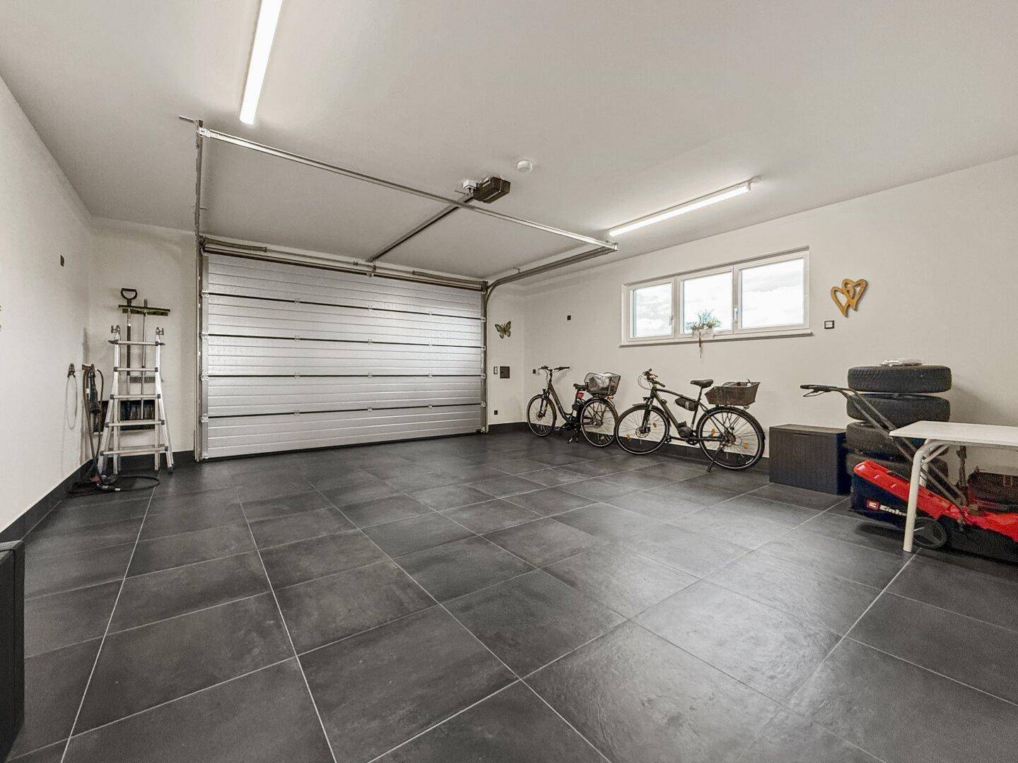 Große Garage mit Rolltor, ausreichend Platz für Fahrzeuge und Fahrräder.
