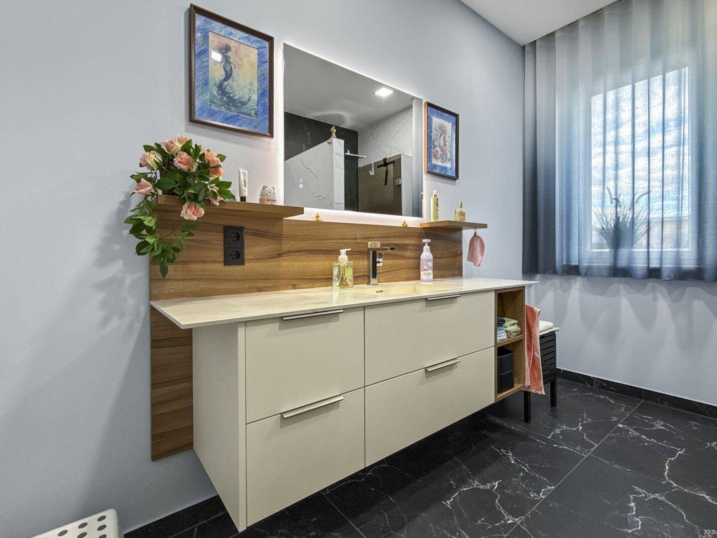 Helles Badezimmer mit modernem Waschtisch, großem Spiegel und Marmorboden.