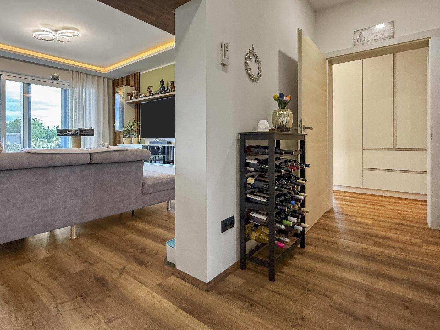 Moderner Wohnbereich mit Holzboden, Sofa und einem praktischen Weinregal als Raumteiler.