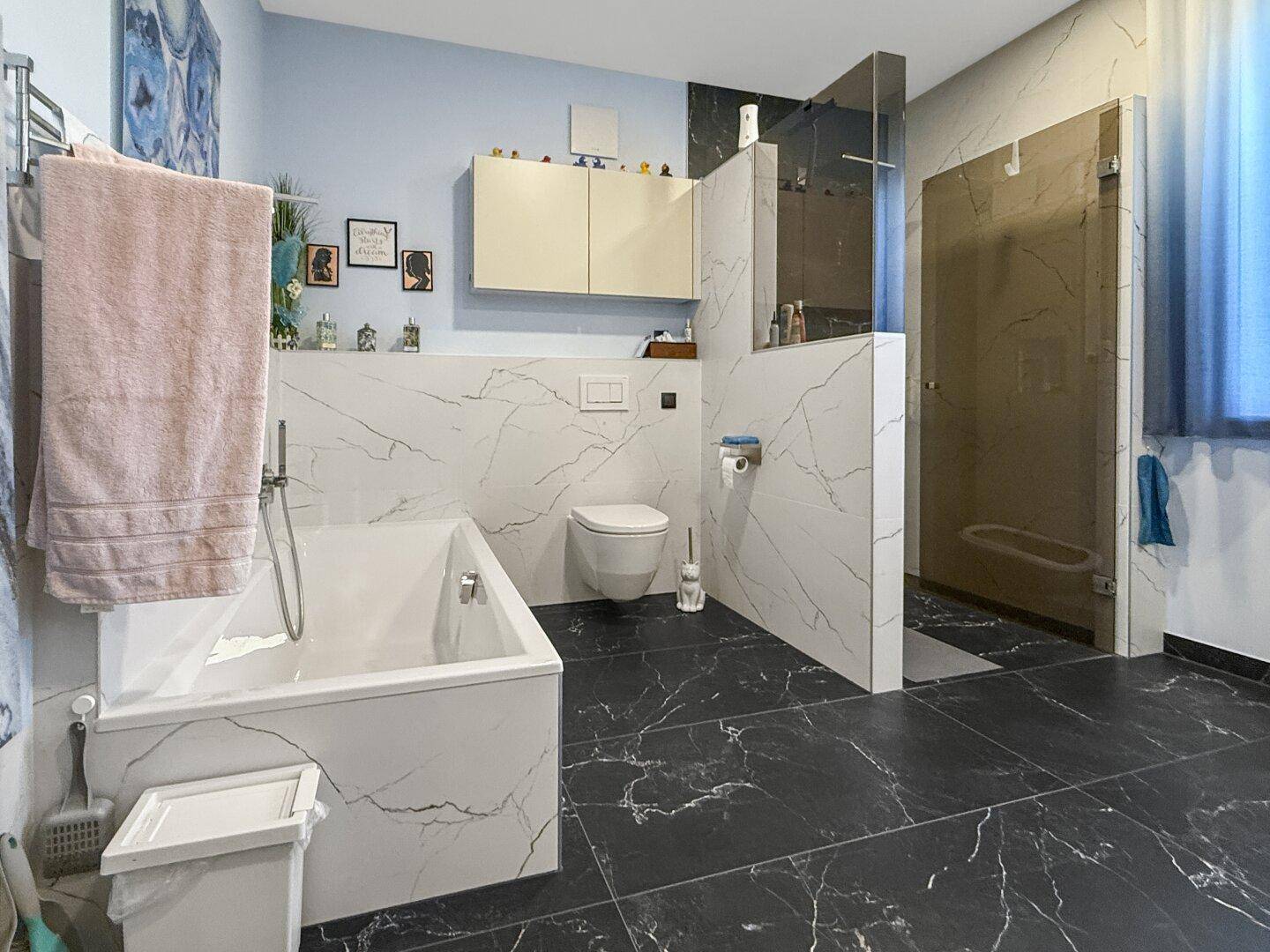 Geräumiges Badezimmer mit Badewanne, Wand-WC und einer modernen begehbaren Dusche.