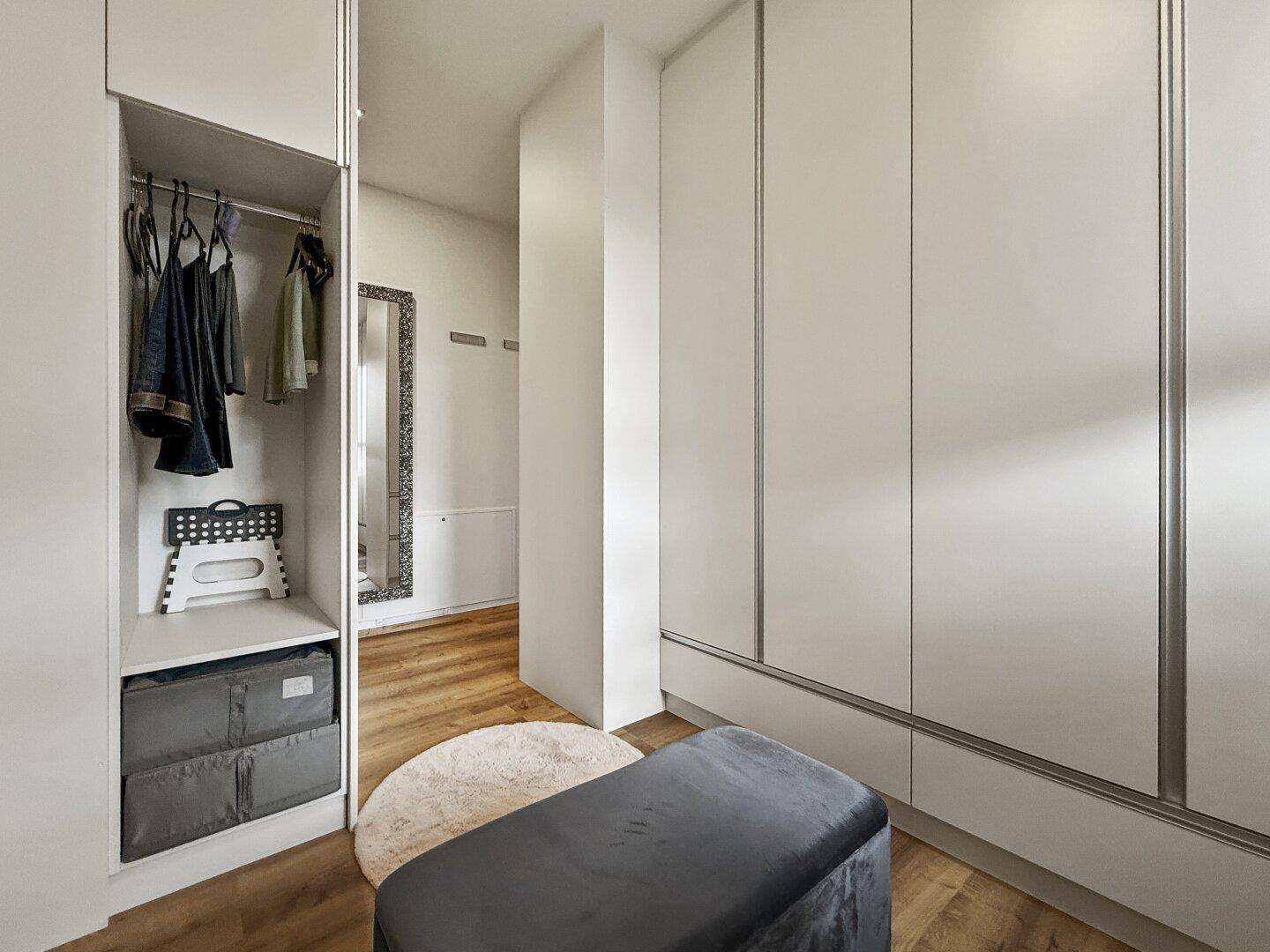 Begehbarer Kleiderschrank mit offenen und geschlossenen Schränken sowie einer Sitzbank.