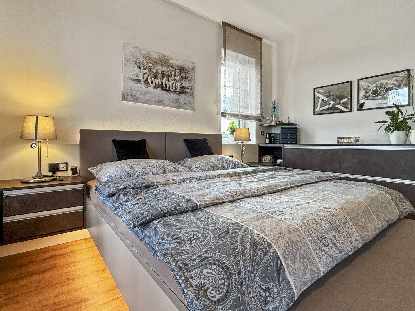 Komfortables Schlafzimmer mit großem Bett, Holzboden und stilvollen Möbeln für eine entspannte Atmosphäre.