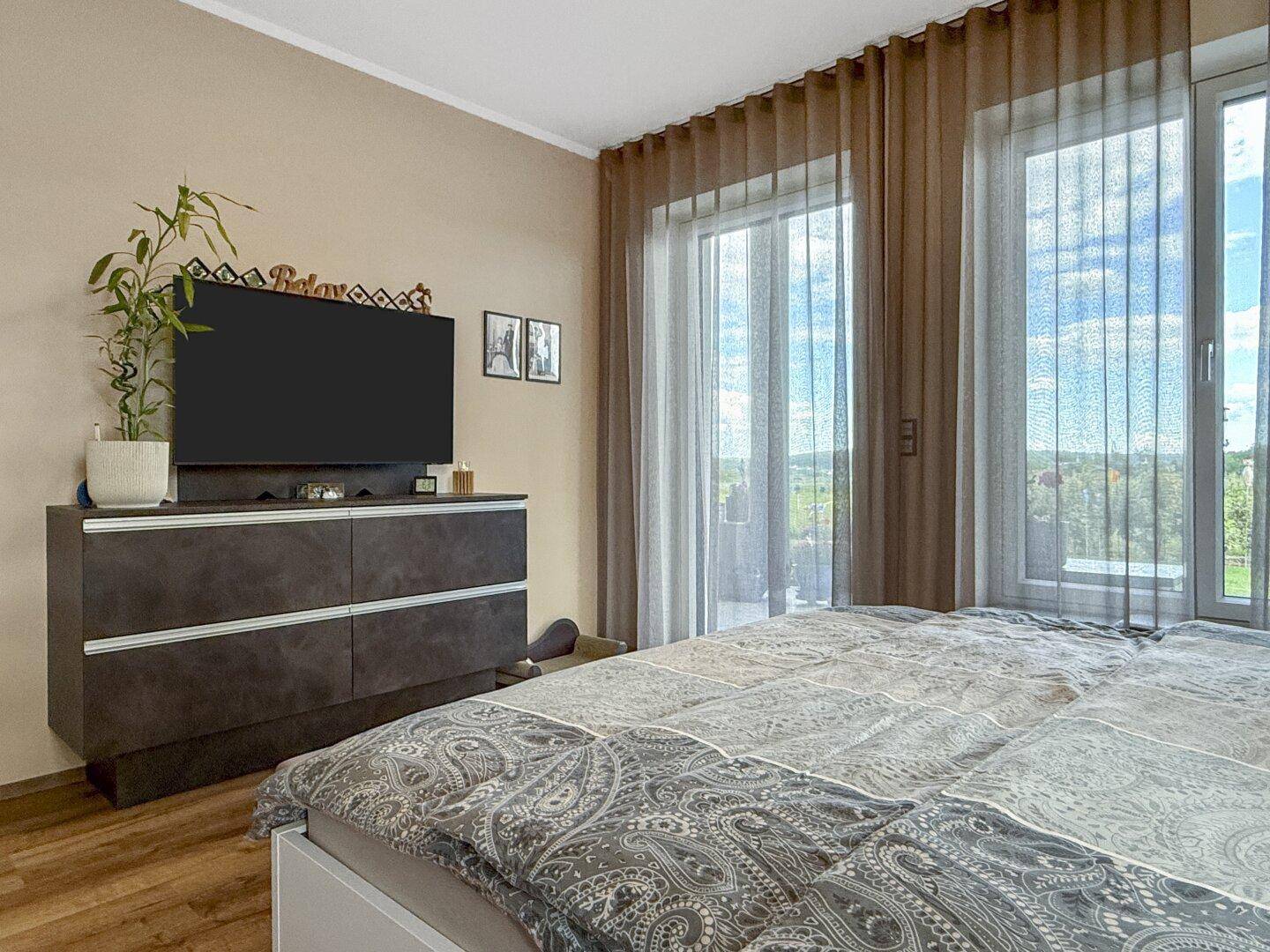 Helles Schlafzimmer mit Zugang zum Balkon und einem schönen Blick ins Grüne.