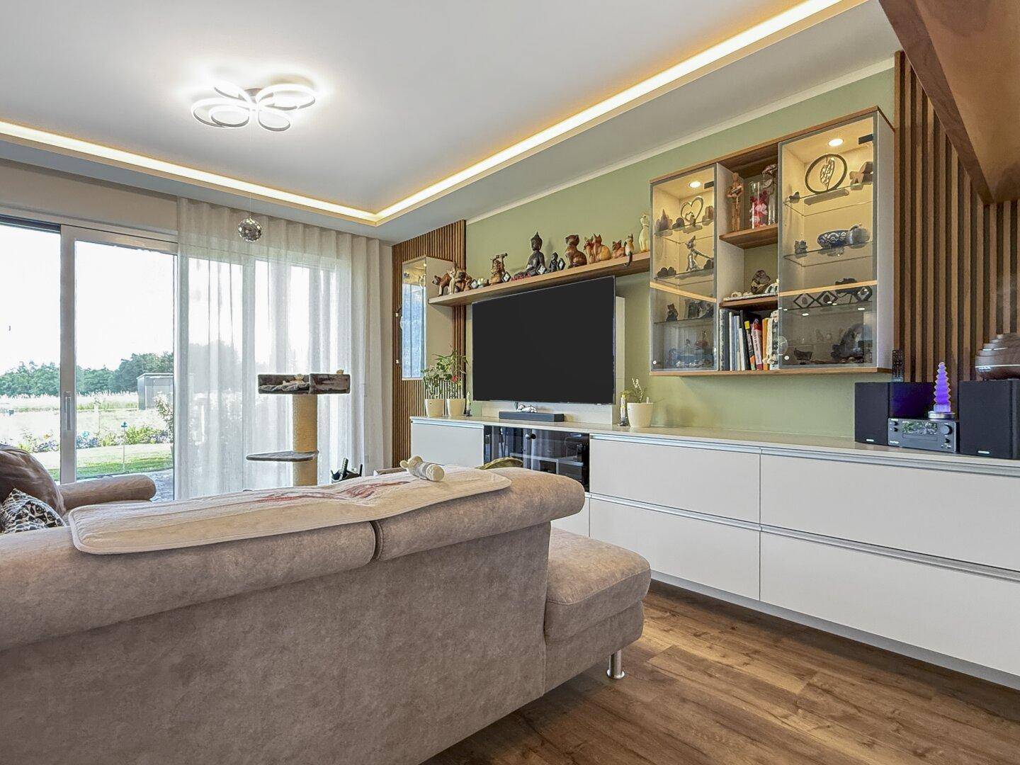Wohnzimmer mit großen Schiebetüren zur Terrasse, Holzboden und moderner Einrichtung.