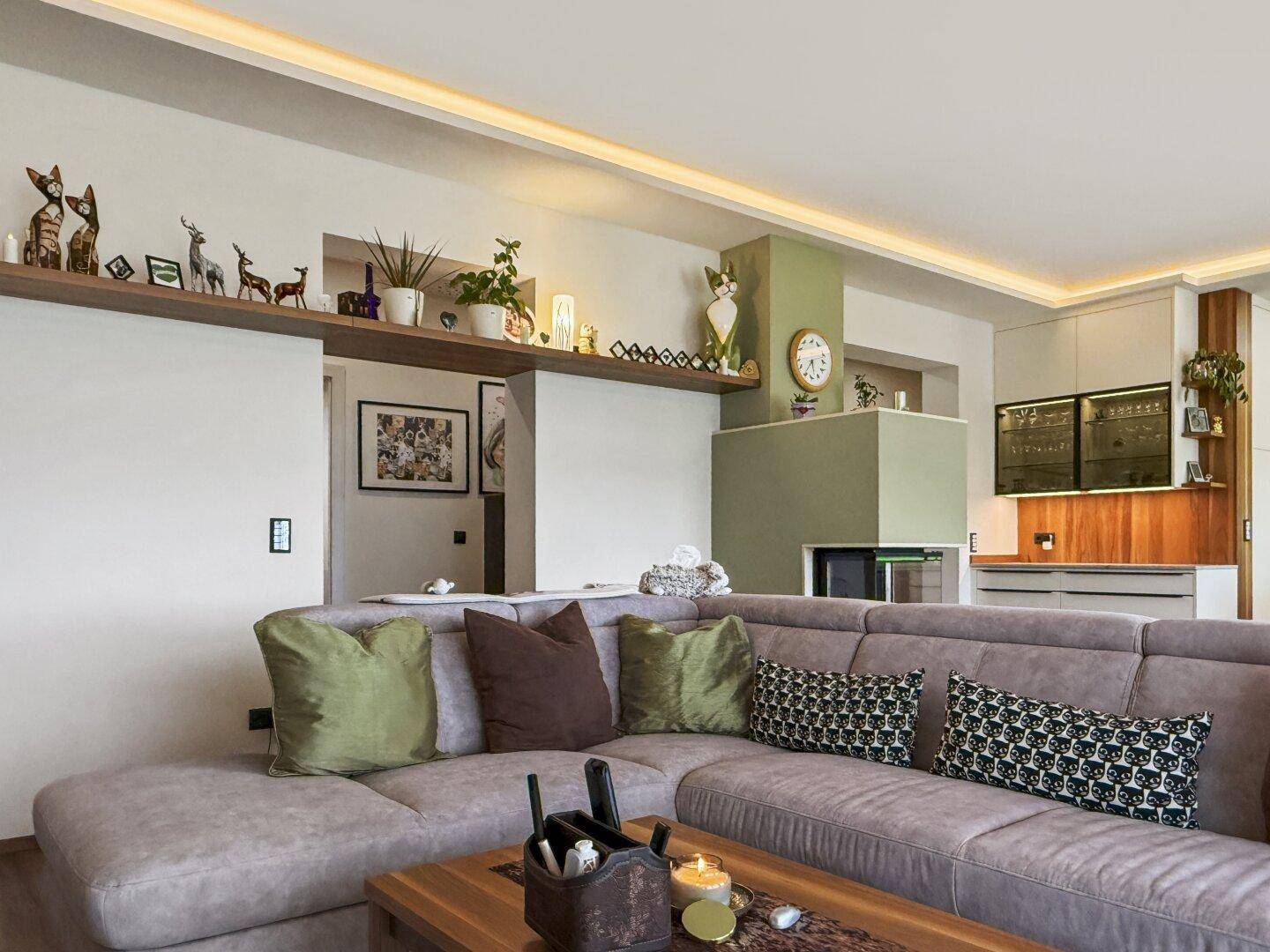 Gemütliches Wohnzimmer mit großem Ecksofa, Holzboden und dekorativen Regalen an der Wand.