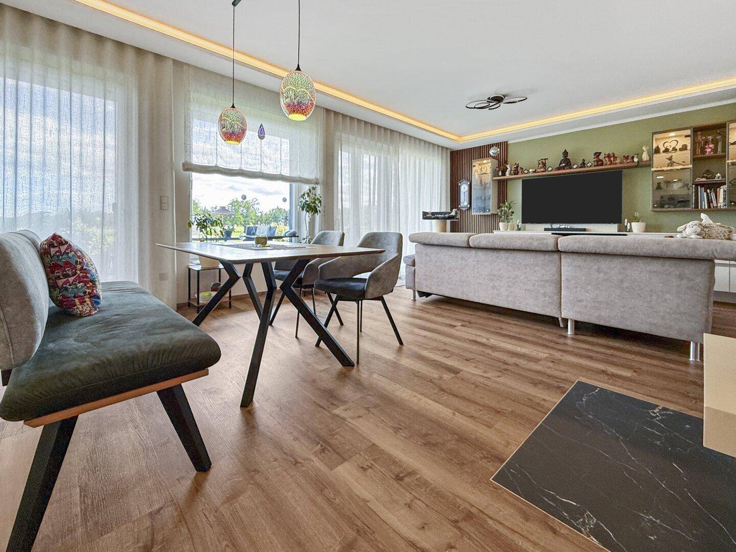 Heller Wohn-Essbereich mit großen Fenstern, Holzboden und Zugang zur Terrasse.