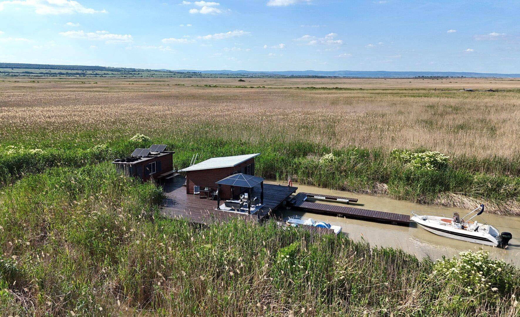 Nahaufnahme aus der Luft zeigt das Anwesen mit Steg, Boot und Solaranlage am See.