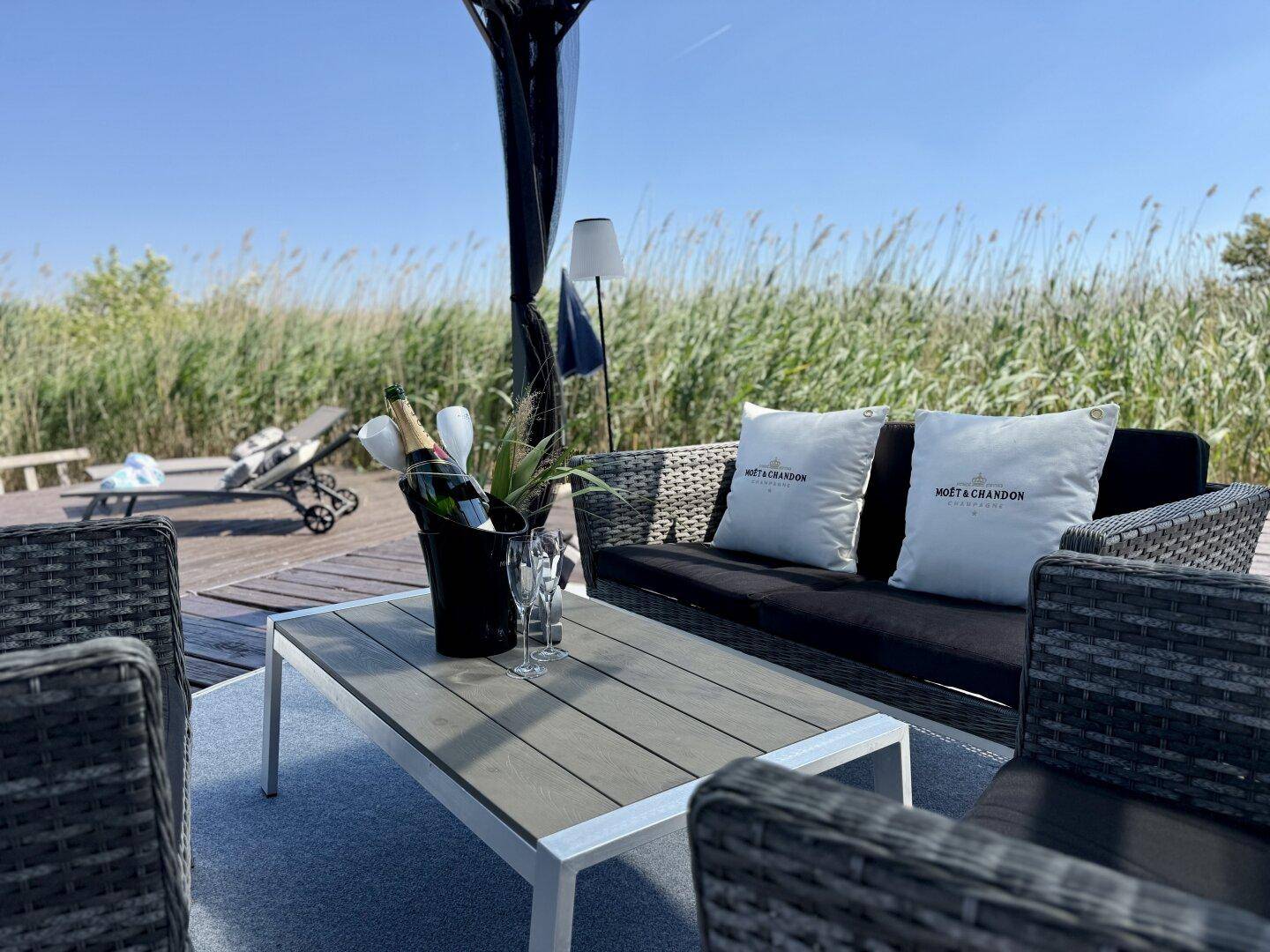 Stilvolle Outdoor-Lounge unter dem Pavillon mit bequemen Sitzmöbeln und Blick ins Grüne.