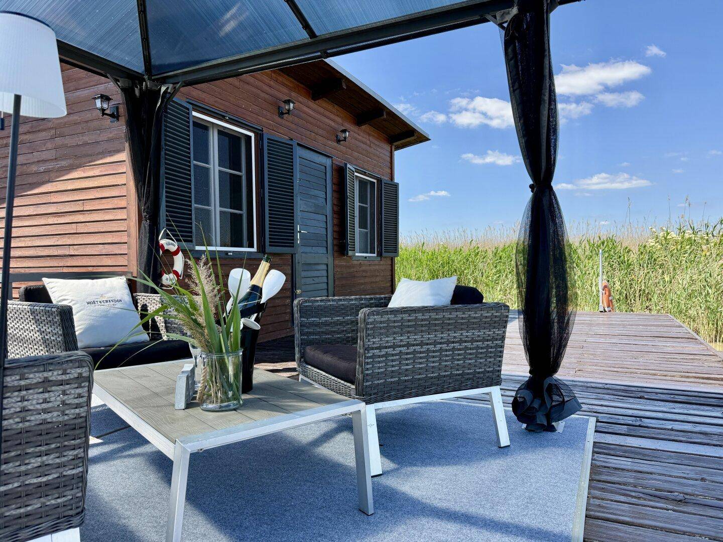 Blick vom Pavillon auf das Holzhaus, mit stilvoller Dekoration auf dem Couchtisch.