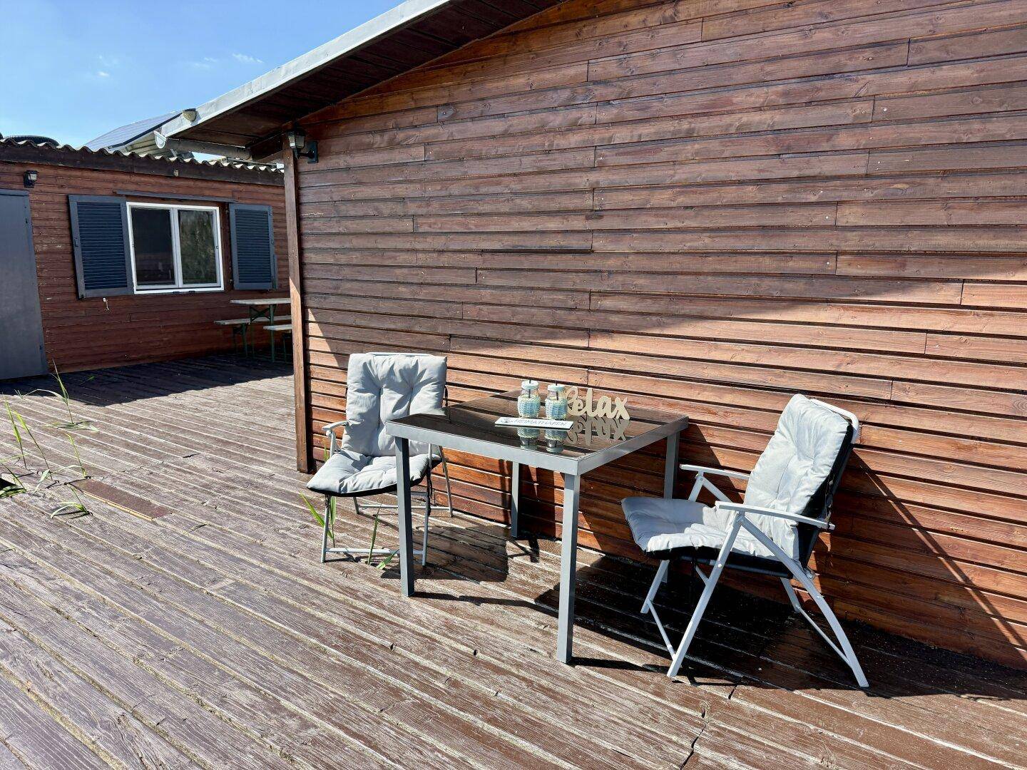 Gemütlicher Essbereich im Freien auf dem Holzsteg, direkt neben dem rustikalen Holzhaus.