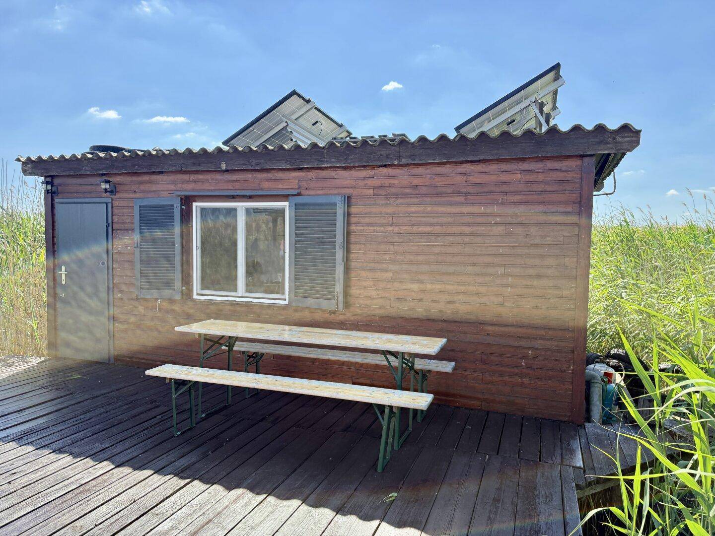 Rustikales Holzhaus mit Solarpaneelen und einem Picknicktisch auf dem Holzsteg.