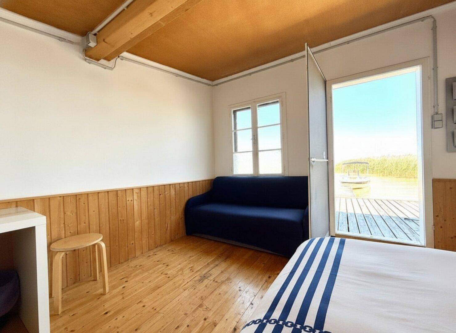 Heller Wohnbereich mit Holzboden, Sofa und direktem Zugang zur Außenterrasse.