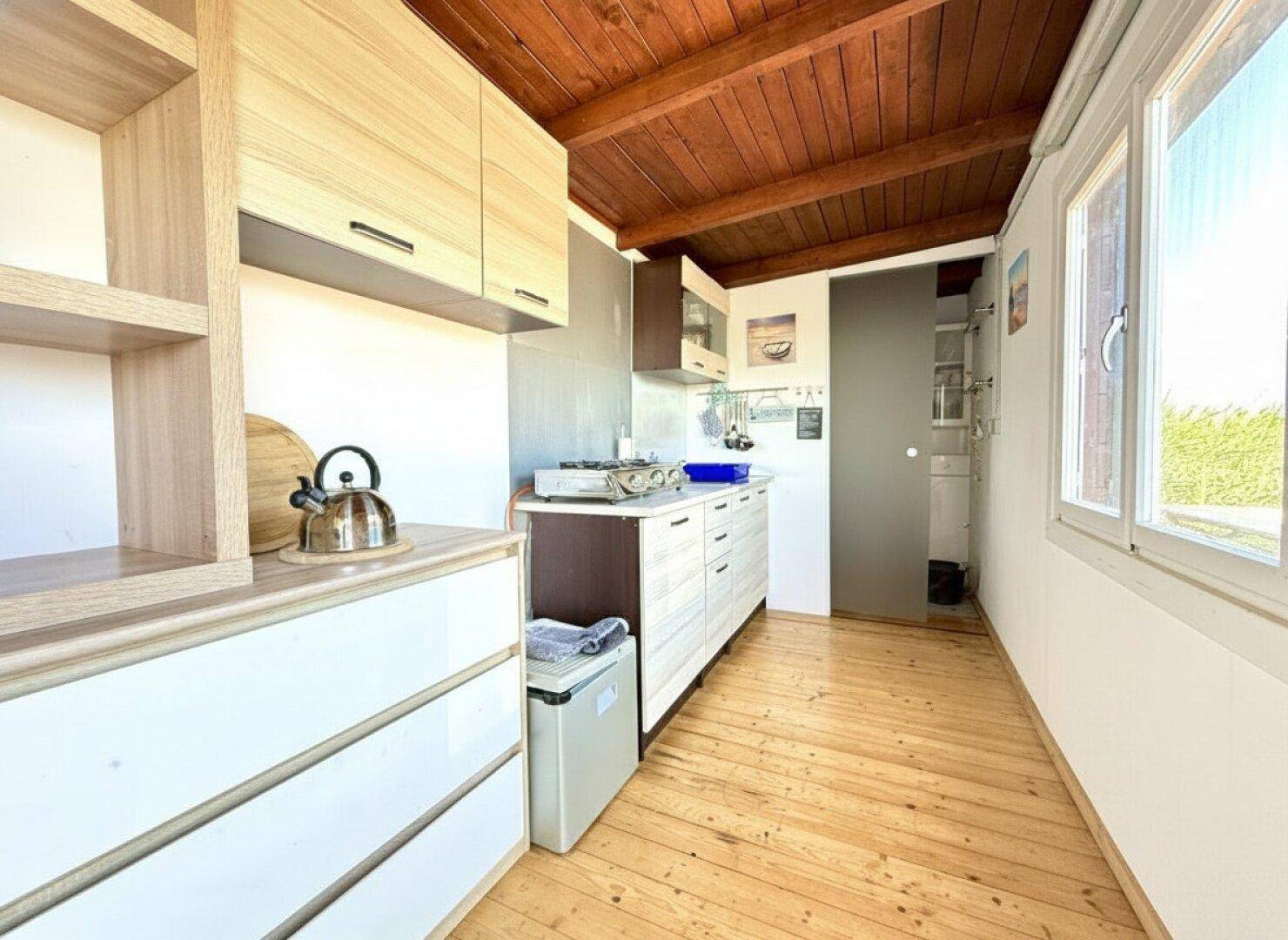 Kleine, funktionale Küche mit Holzschränken, Gasherd und Holzboden in rustikalem Stil.