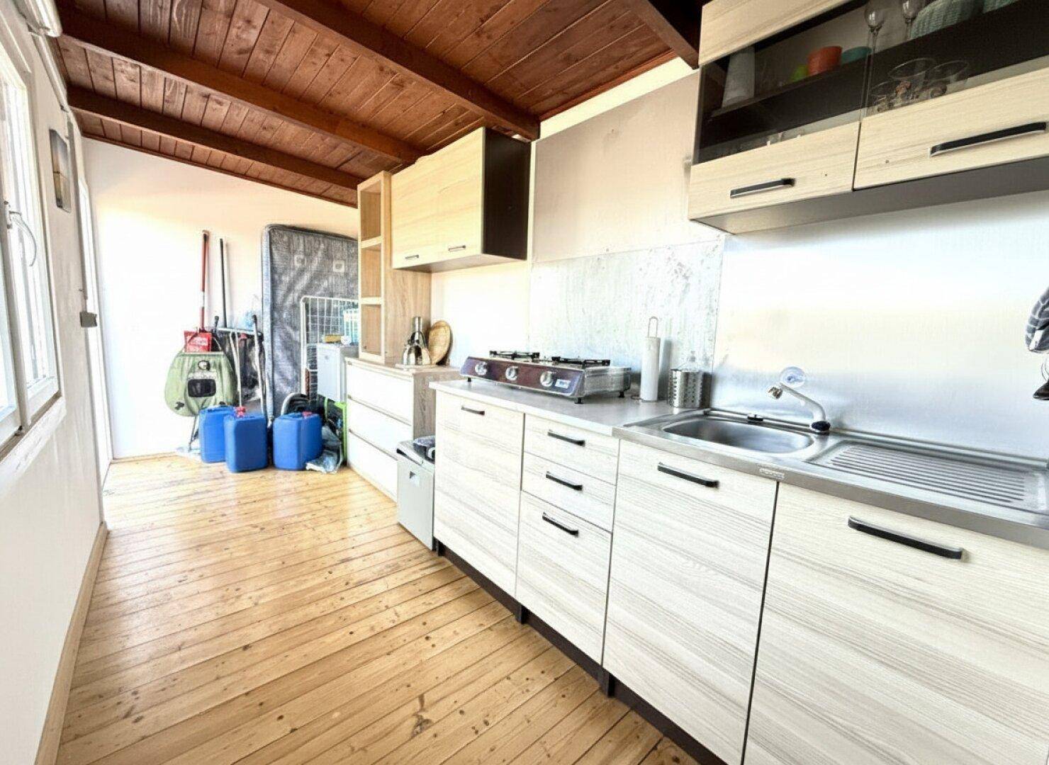 Schmale Küche mit Holzschränken, Spüle und Gasherd, ideal für kompaktes Wohnen.