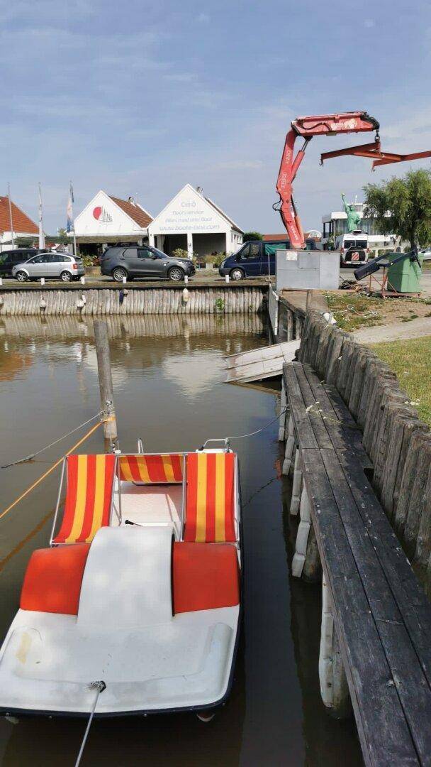 Ein Tretboot liegt im Kanal, im Hintergrund sind Gebäude und ein Kran zu sehen.