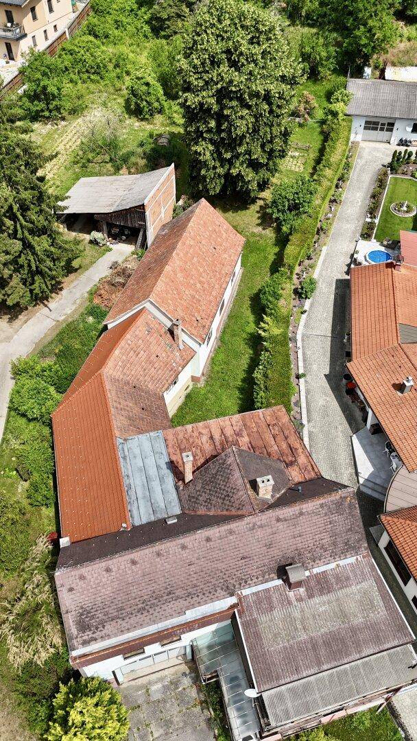 Luftaufnahme des Anwesens mit mehreren Dächern und umgebender grüner Landschaft.