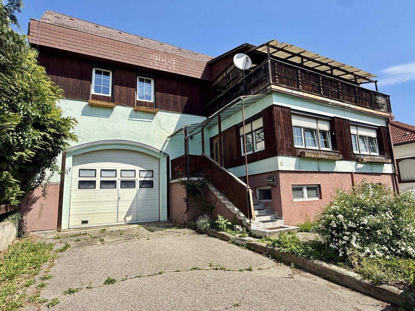 Gesamtansicht des Hauses mit Garage, Balkon und gepflasterter Zufahrt.