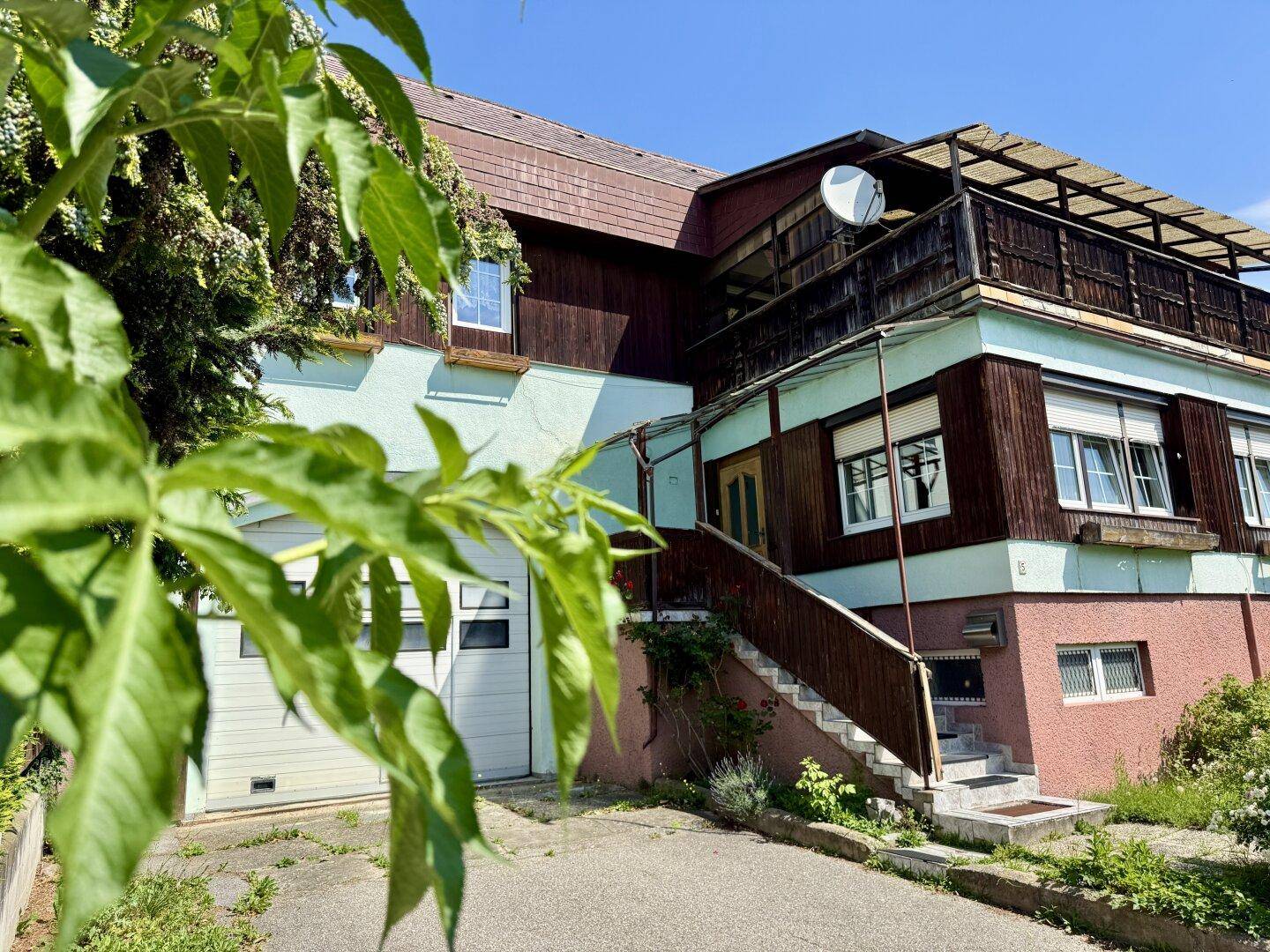 Nahaufnahme der Hausfassade mit Garage, Außentreppe und Balkon.
