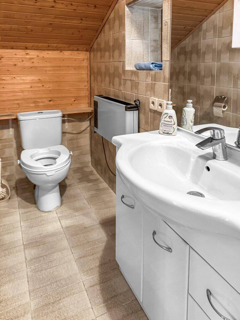 Badezimmer im Dachgeschoss mit Waschbecken, Toilette und Holzverkleidung.