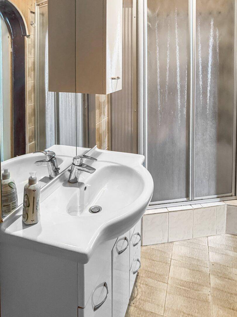 Badezimmer mit Waschbecken, Spiegelschrank und Duschkabine.