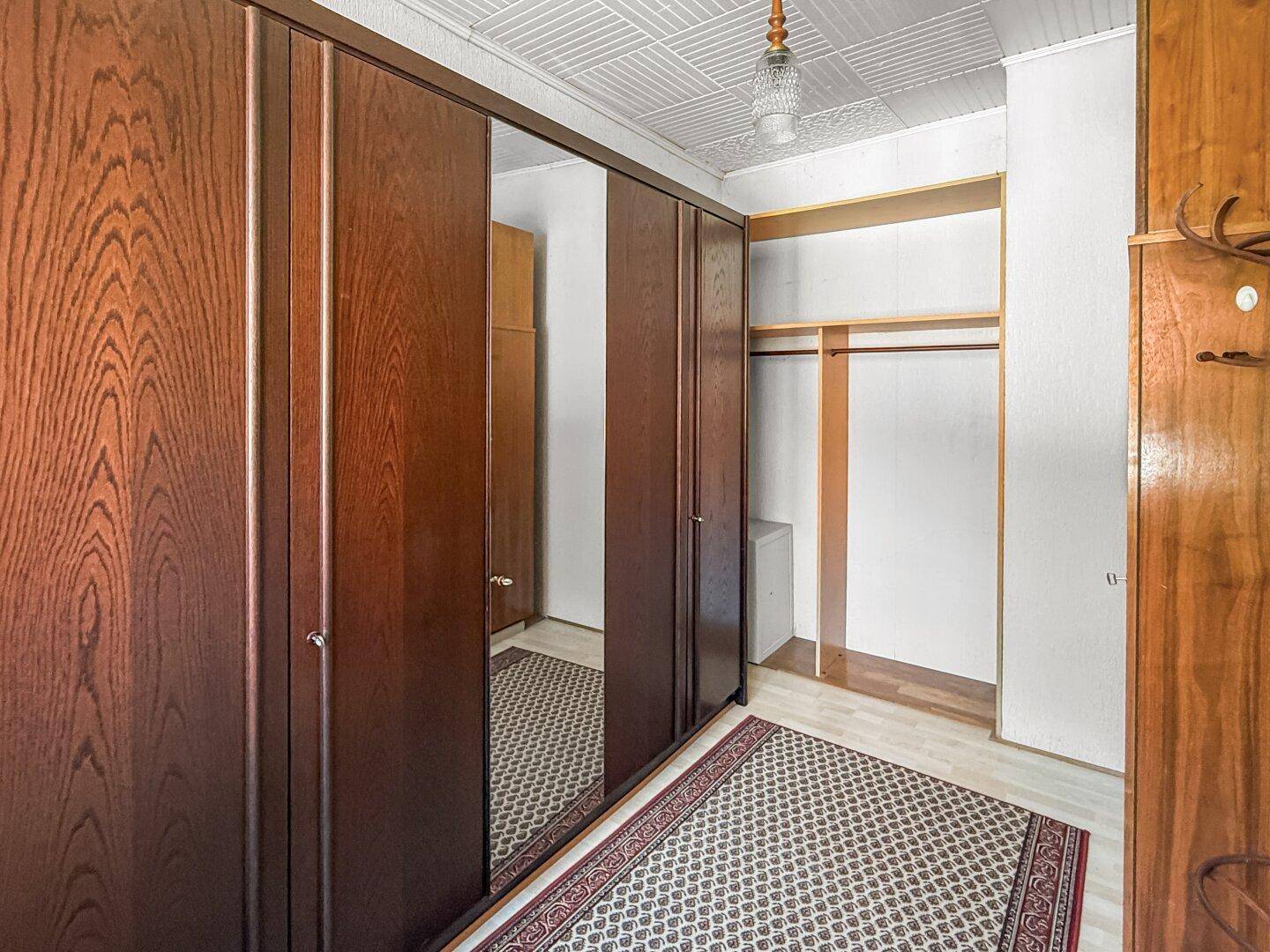 Schlafzimmerbereich mit großem Holzschrank und Spiegeltüren.