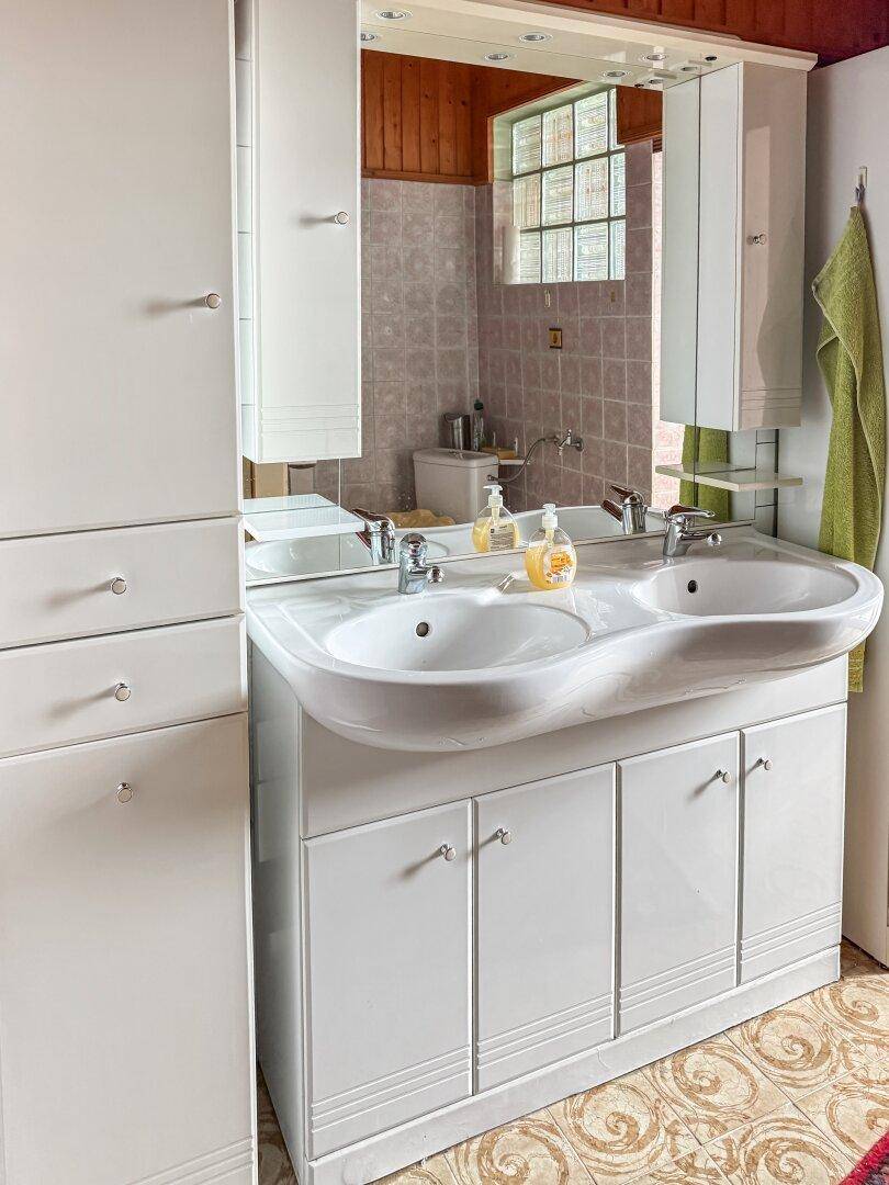 Badezimmer mit Doppelwaschbecken, Spiegelschrank und hellen Fliesen.