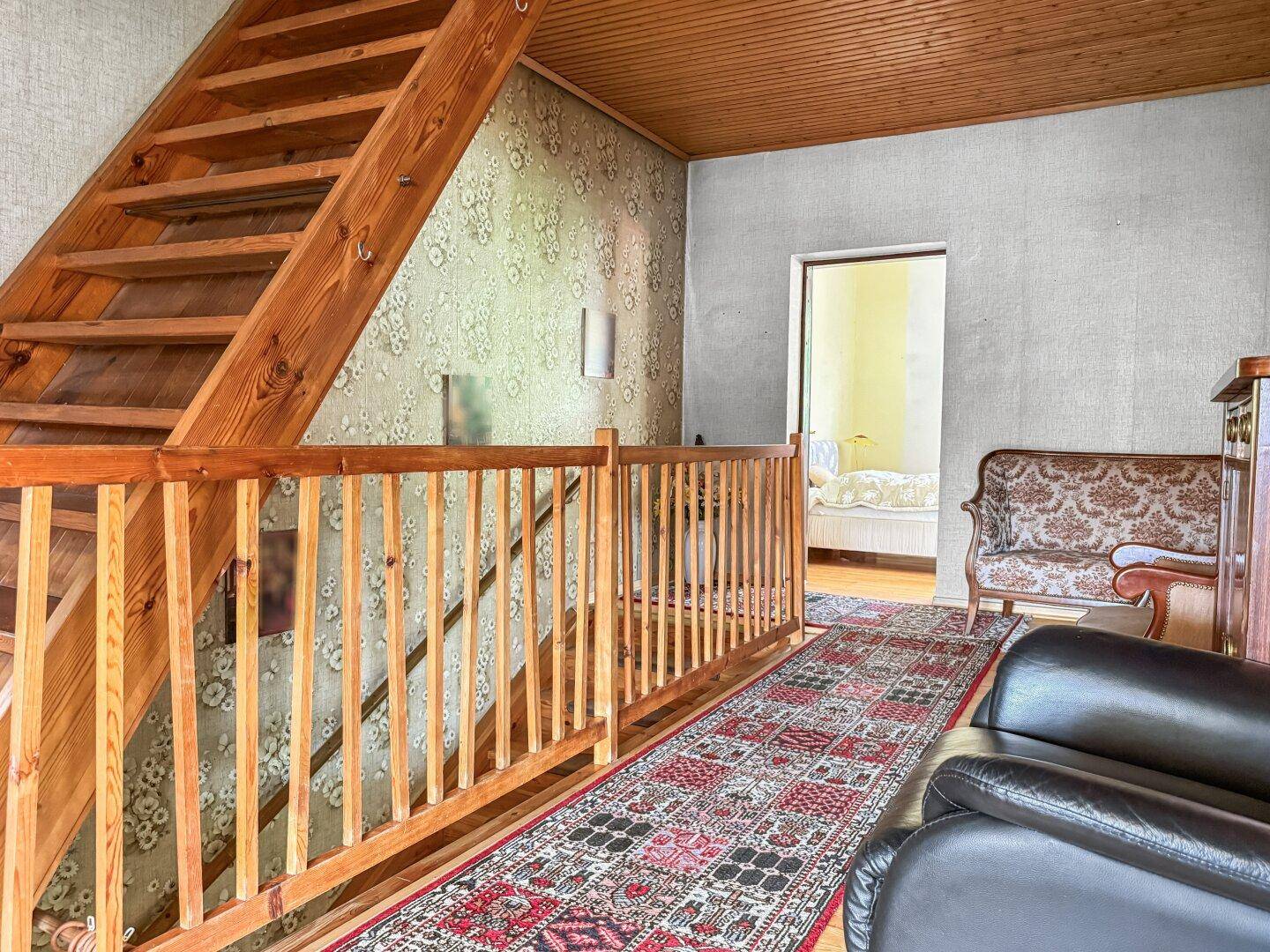 Obergeschoss-Flur mit Holzgeländer, Teppichläufer und Blick in ein weiteres Zimmer.