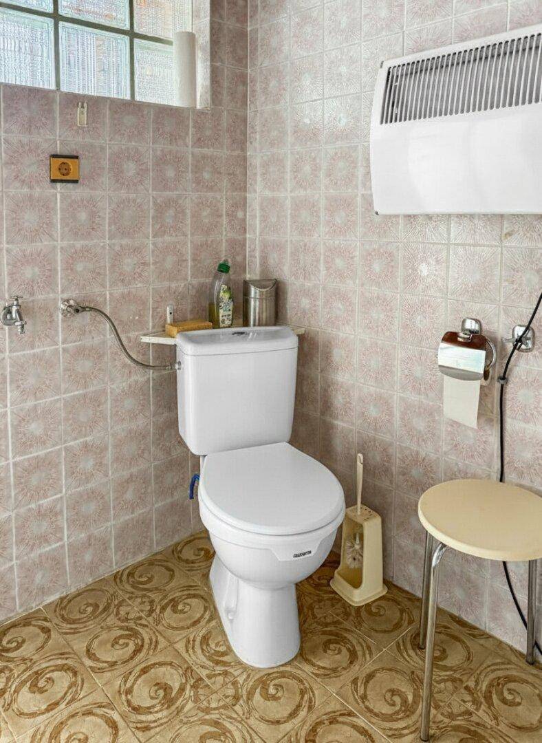 Toilette mit Heizkörper und gemusterten Fliesen im Badezimmer.