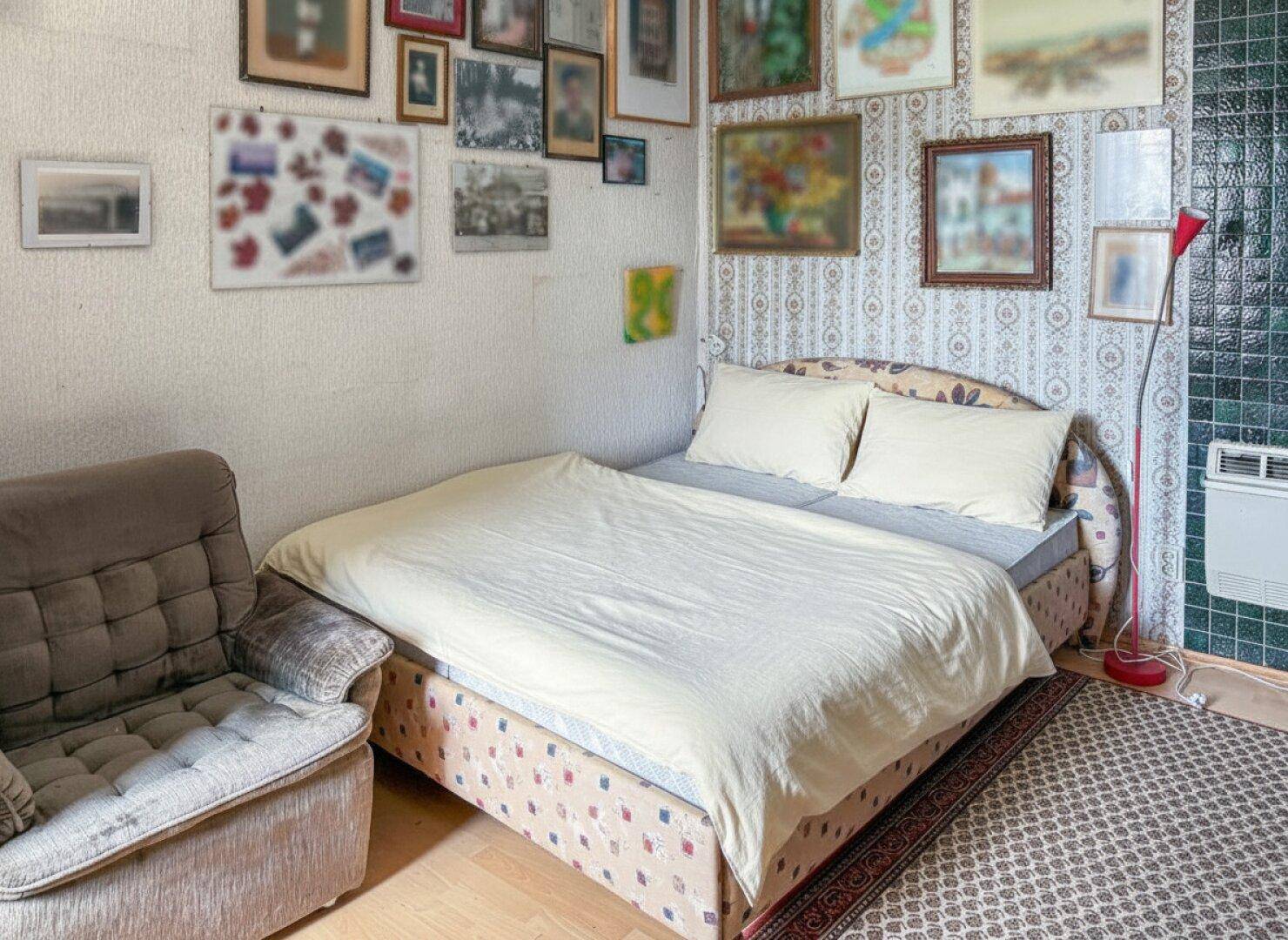 Gemütliches Schlafzimmer mit Bett, Sofa und einer Wand voller gerahmter Bilder und Tapetenmuster.