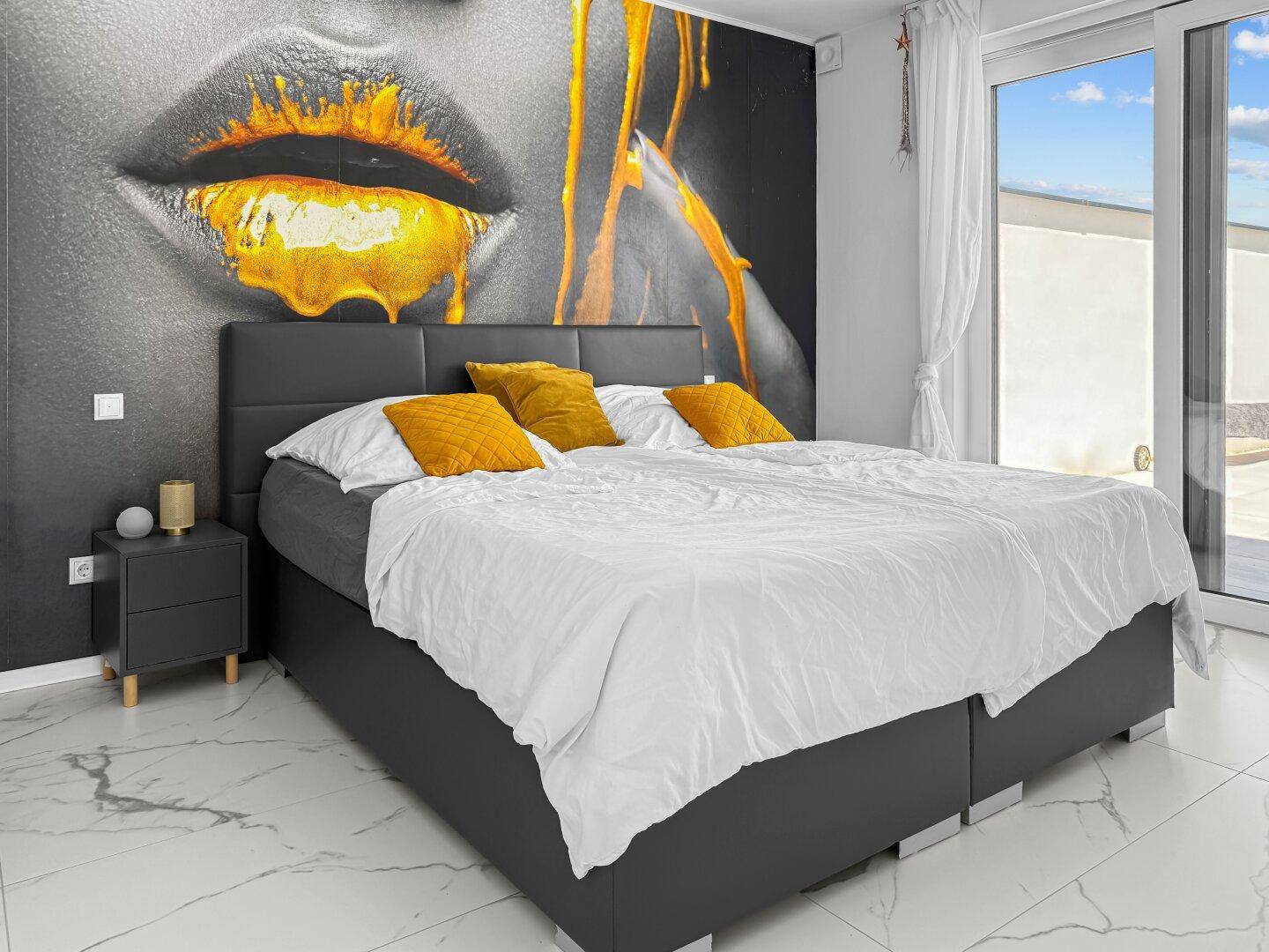 Modernes Schlafzimmer mit großem Bett, auffälliger Wandmalerei und Zugang zur Terrasse.